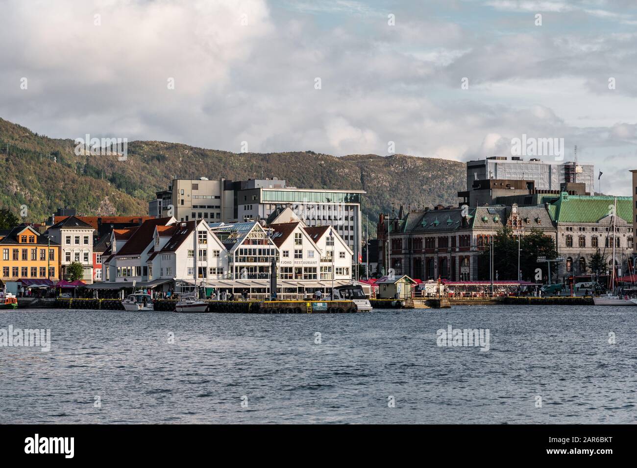 Éditorial 09.03.2019 Bergen Norvège, Restaurant Fjord avec des gens marchant sur la jetée et la chaîne de montagne en arrière-plan Banque D'Images