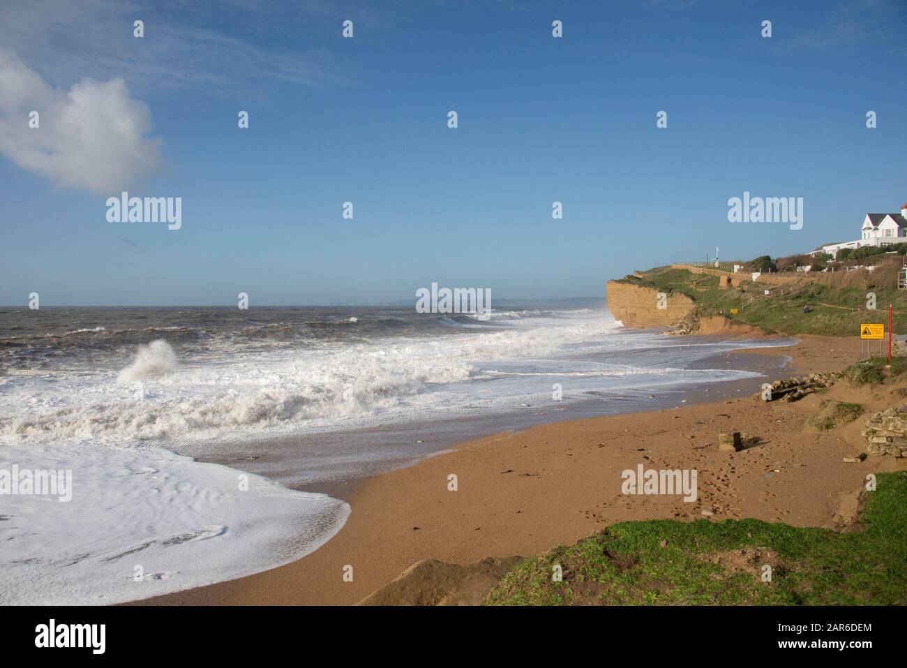 De hautes vagues blanches qui jetent les falaises de plage et de grès à marée haute lors d'une belle journée à Hive Beach, près de West Bay, Dorset, janvier Banque D'Images