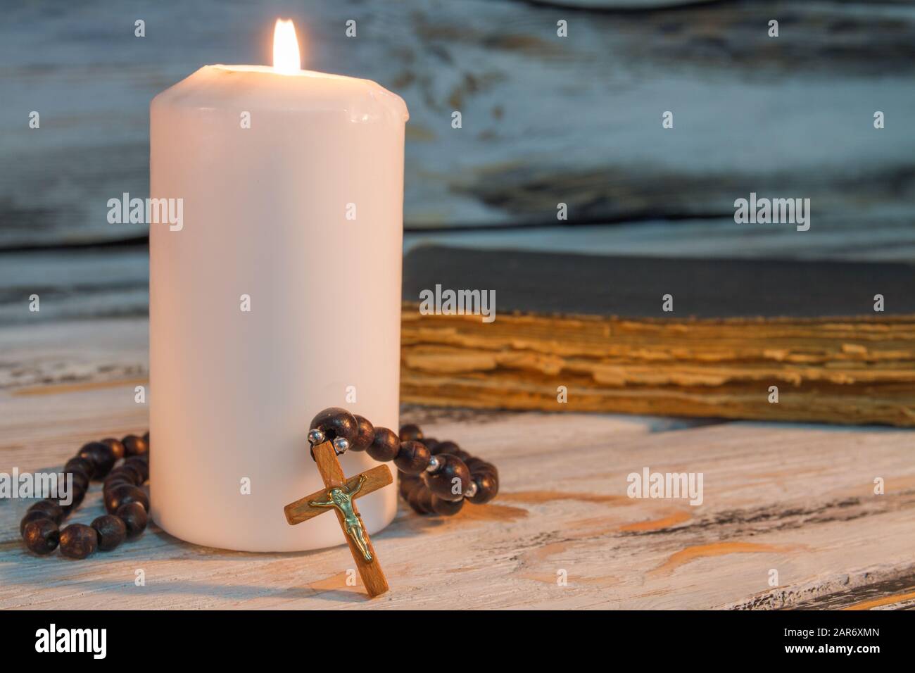 Bougie brûlante et rosaire avec croix crucifix. Banque D'Images