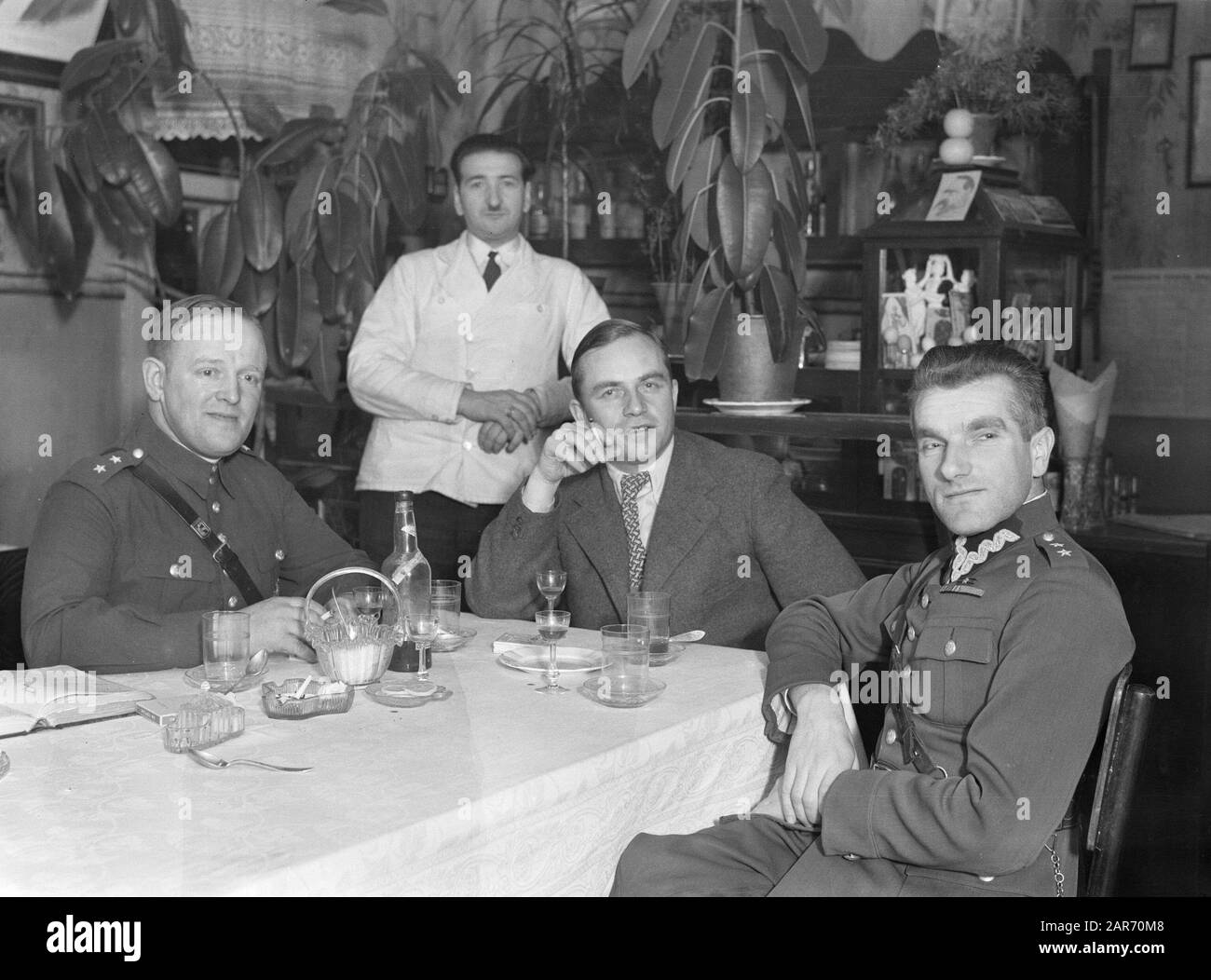 Voyage En Lituanie Novy Troky (Trakai). Deux lieutenants de l'armée polonaise et un civil à la table dans un restaurant alors que le serveur regarde Annotation: Van de Poll notes: Gauche Oberl. Ludwick Pagowski et Oberl droit. Stanislaw Laurentowski, Brygaada K.o.p. Date : 1934 lieu : Lituanie, Pologne mots clés : personnel d'accueil, militaire, officiers, restaurants Banque D'Images