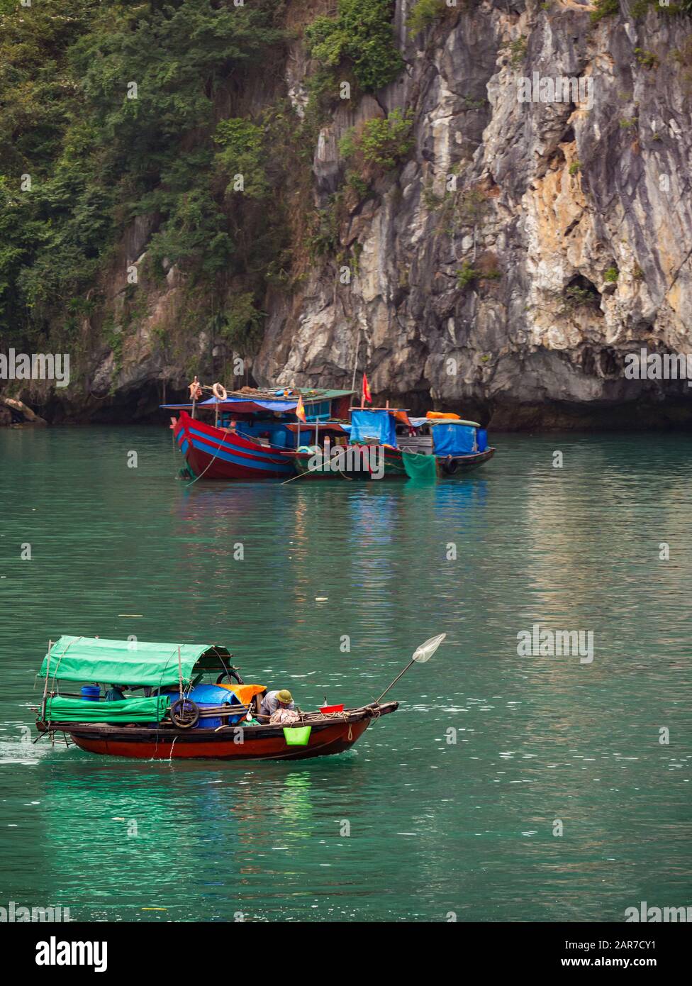 Bateaux de pêche traditionnels avec falaise de karst de roche calcaire, baie de Halong, Vietnam, Asie Banque D'Images