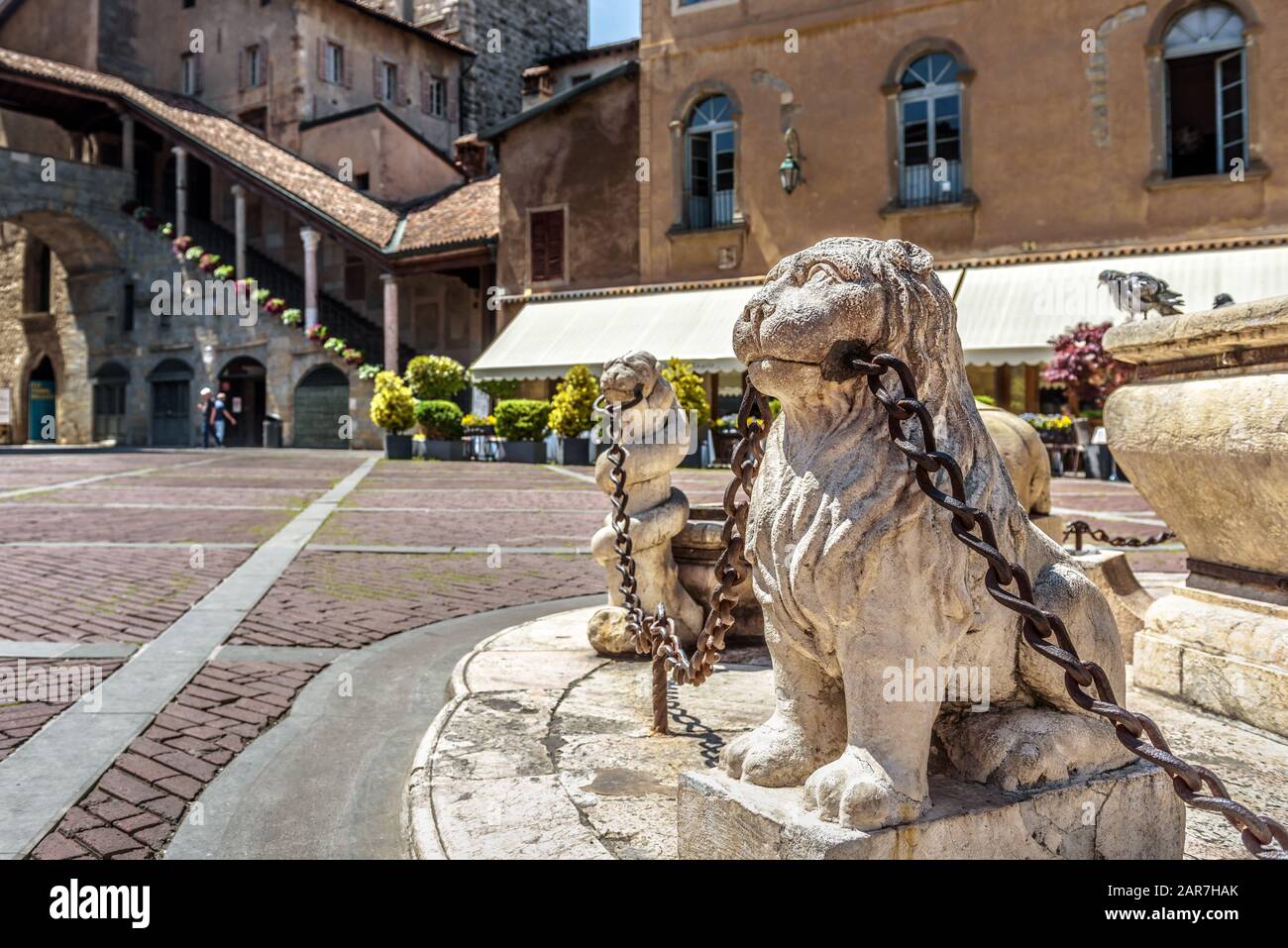 Bergame en été, Italie. Piazza Vecchia Dans Citta Alta Ou Upper City. Statues de Lion avec chaînes à la fontaine ancienne dans l'ancien centre de Bergame. Banque D'Images