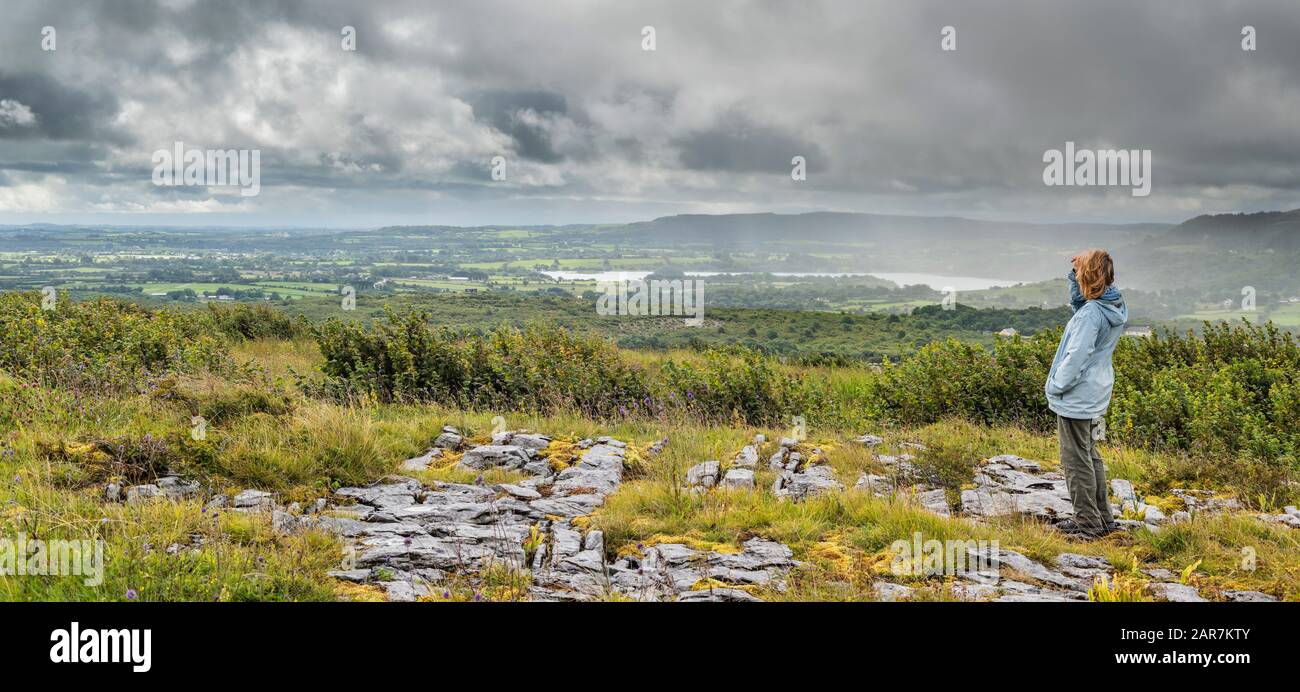 Une touriste féminine prend la vue de Parknabinna dans le pavé calcaire du Burren au-dessus du grès et du schiste du sud de Clare Banque D'Images