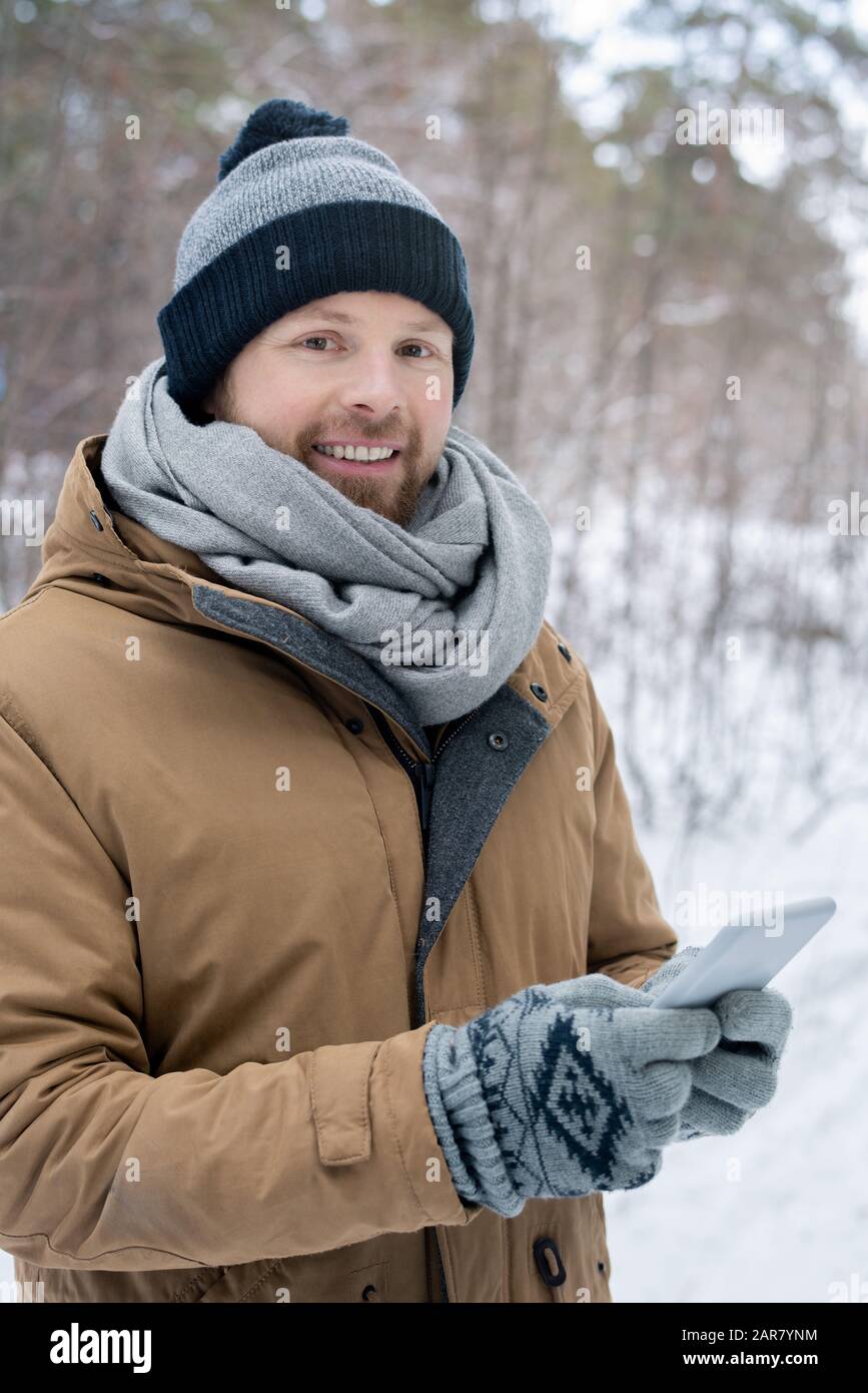 Jeune homme en bonnet gris, écharpe, gants veste chaude défilant dans  smartphone Photo Stock - Alamy