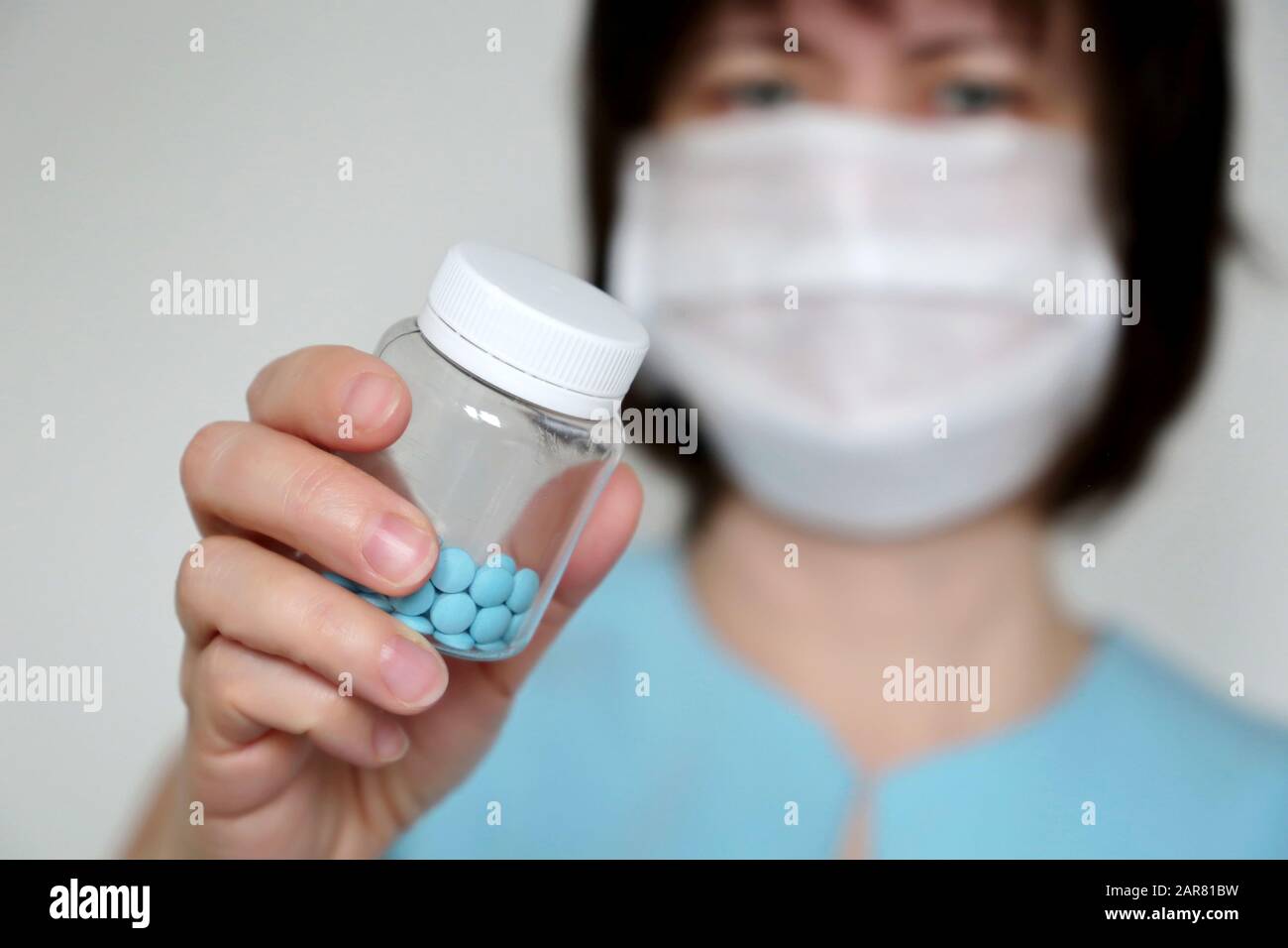 Médecin donnant des pilules, femme dans le masque médical avec bouteille de comprimés bleus. Concept de dose de médicaments, vitamines, examen médical, coronavirus, traitement de la grippe Banque D'Images