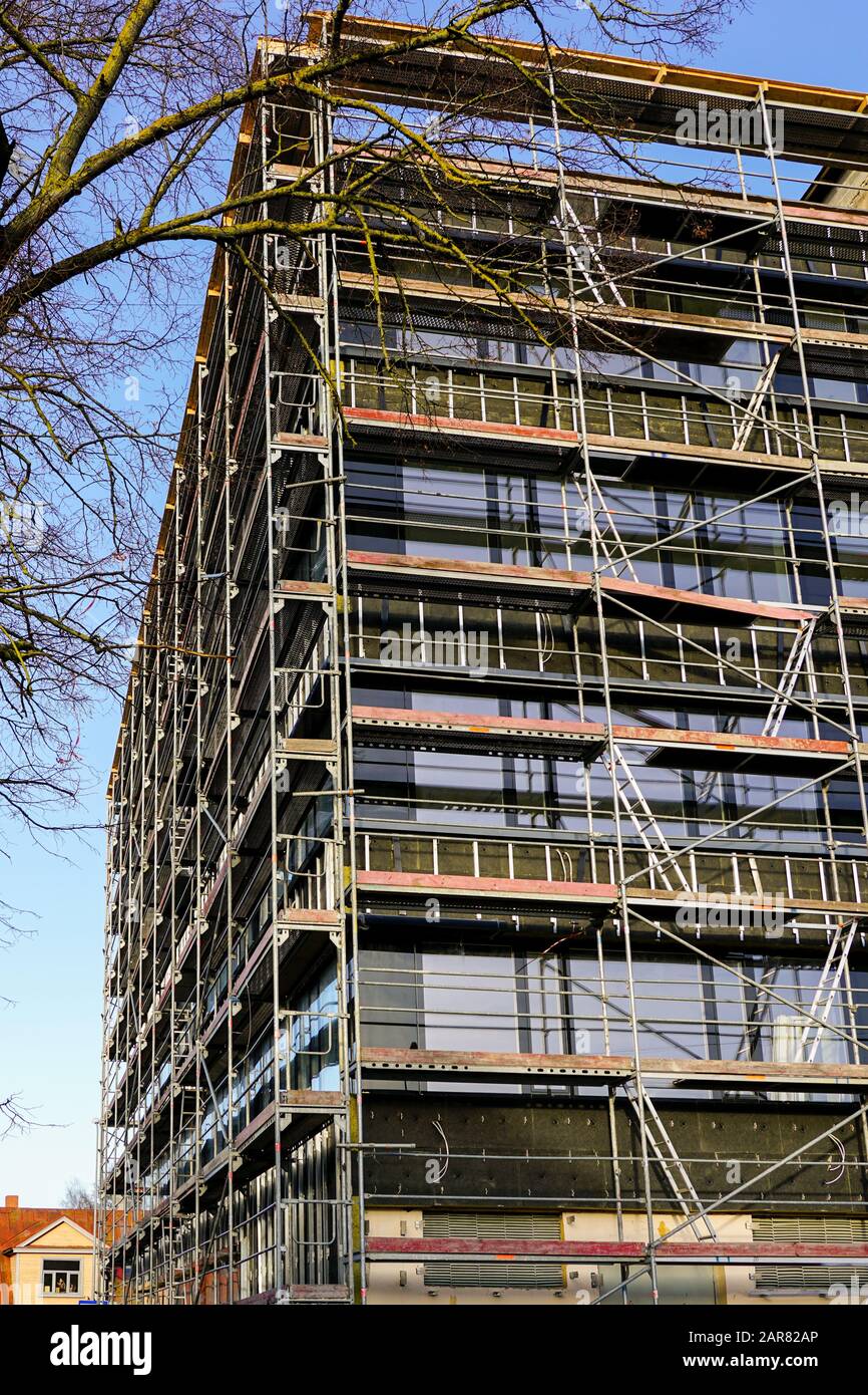 Près de la maison d'échafaudage pour installer l'isolation thermique de la façade de l'immeuble, les travailleurs dans les gilets de sécurité et casques Banque D'Images