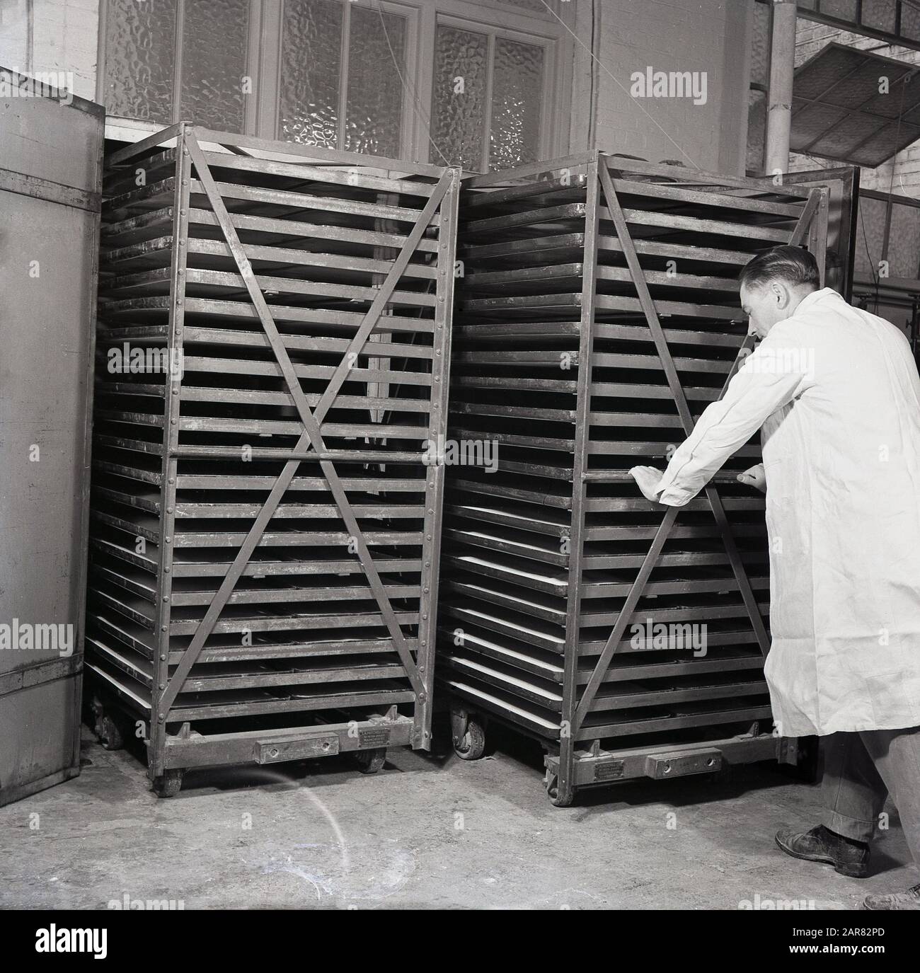 Années 1950, ouvrier historique en manteau blanc déplaçant des armoires