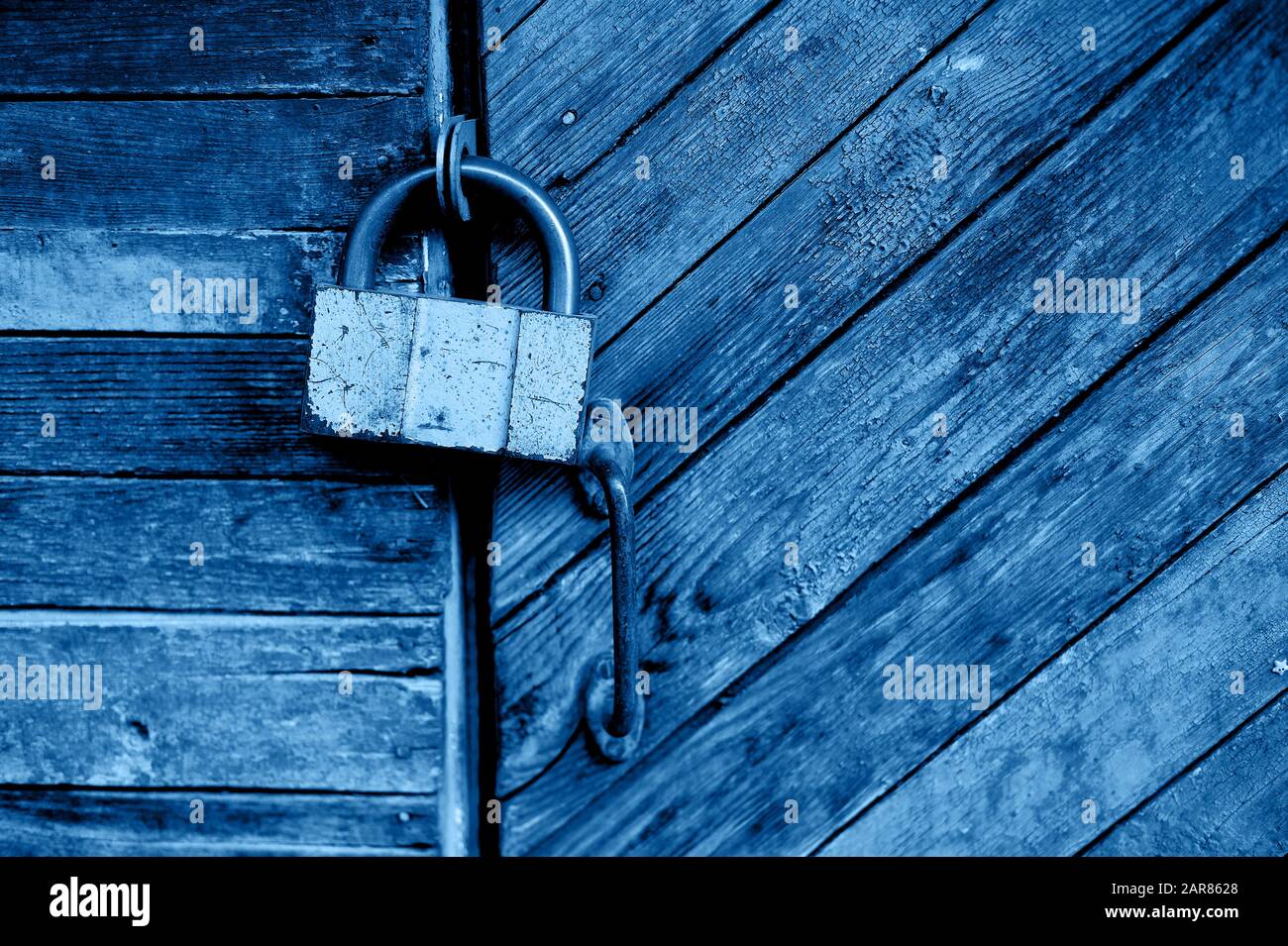 Ancienne porte verte ou mur d'une maison en bois dans le style rustique, avec peinture peeling.sur la porte pend une vieille serrure en métal, bleu classique. La tendance de 2020. Banque D'Images