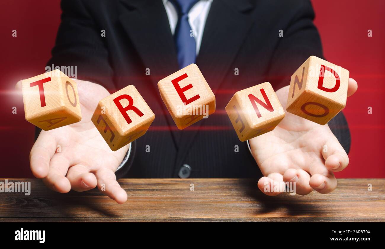 Les cubes lancés par un homme composent le mot tendance. Sujets populaires et pertinents. Nouvelles tendances idéologiques. Prédire la popularité de nouveaux thèmes, styles et tec Banque D'Images