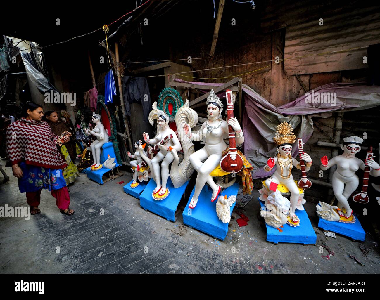Une femme passe devant les idoles de Devi Saraswati pendant les préparatifs du festival.Basant Pancani ou Vasant Pancami est un festival hindou qui célèbre la venue du printemps en Inde. Banque D'Images