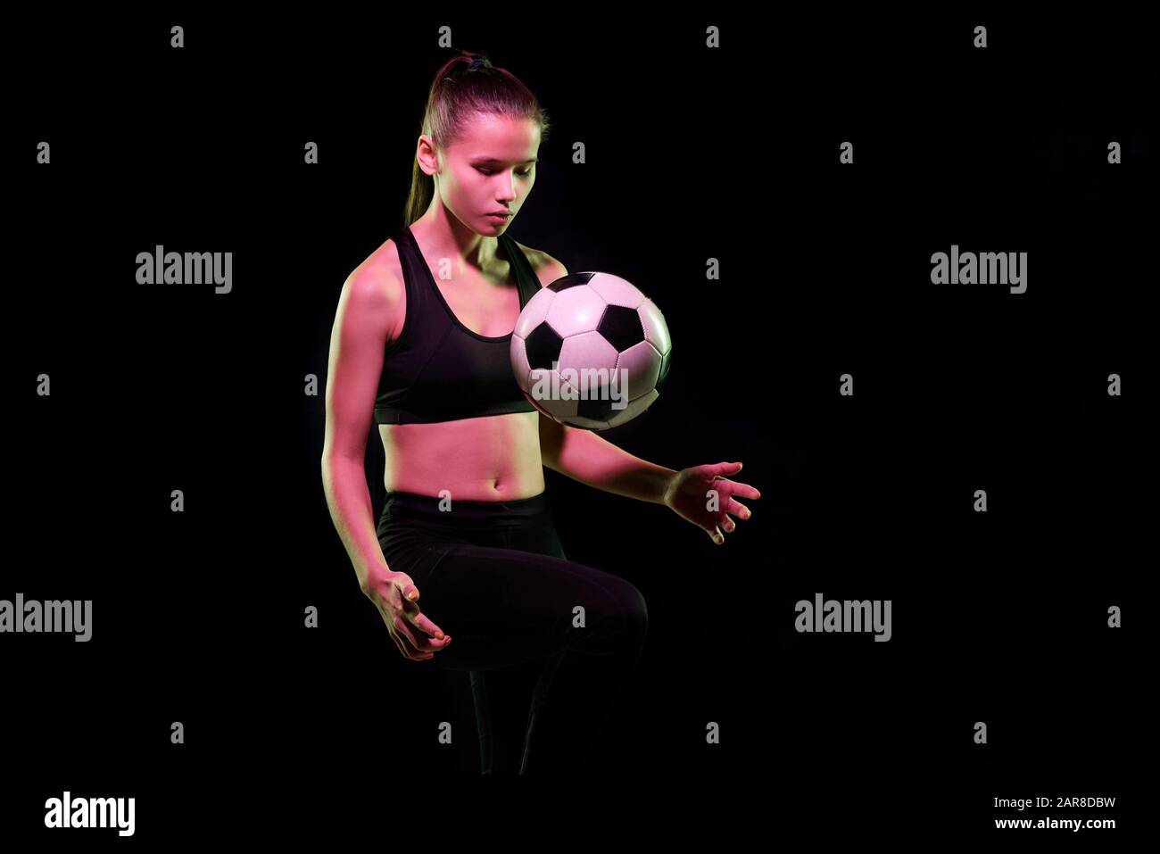 Joli joueur de football féminin dans l'entraînement de vêtements de sport avec ballon de football Banque D'Images
