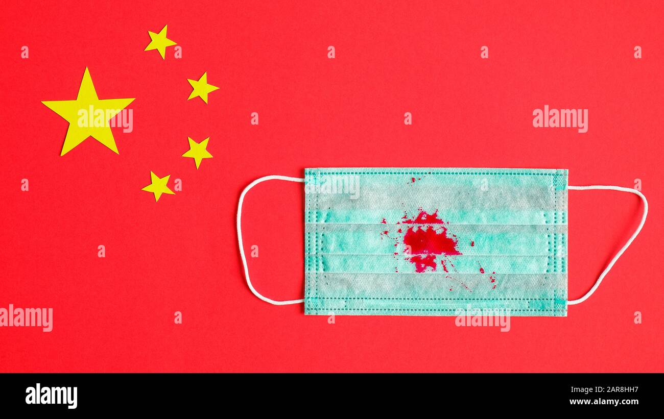 Toux de sang du coronavirus, traces de sang sur le masque respiratoire protecteur sur le drapeau chinois. Vue de dessus. Nouveau Coronavirus chinois 2019-nCoV originaire Banque D'Images