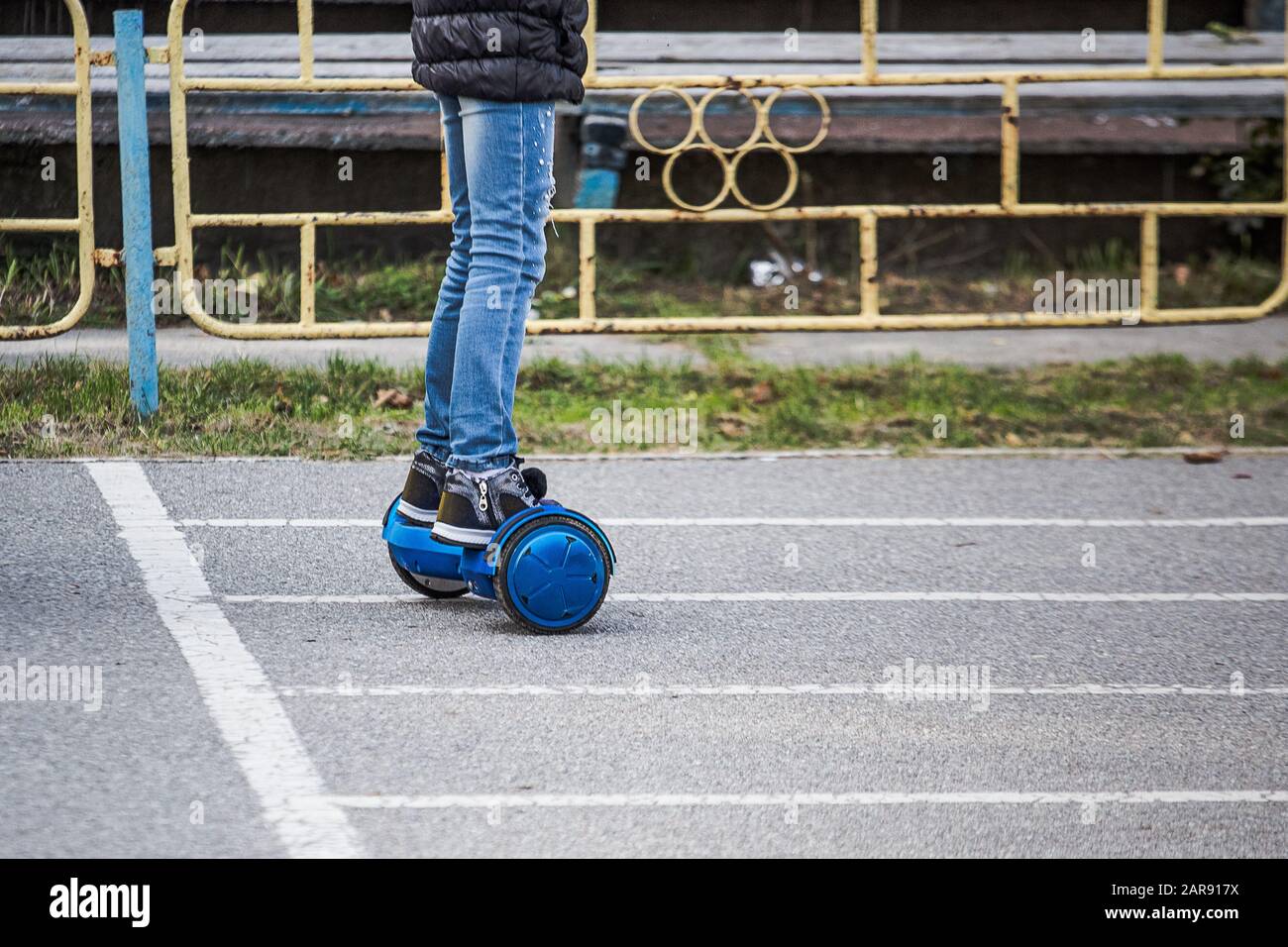 jambes de fille dans un jean déchiré qui monte sur des circuits de  gyrosboard bleus dans le stade de la ville. Planche à deux roues  auto-équilibrée ou scooter de planbord. Électrique Photo
