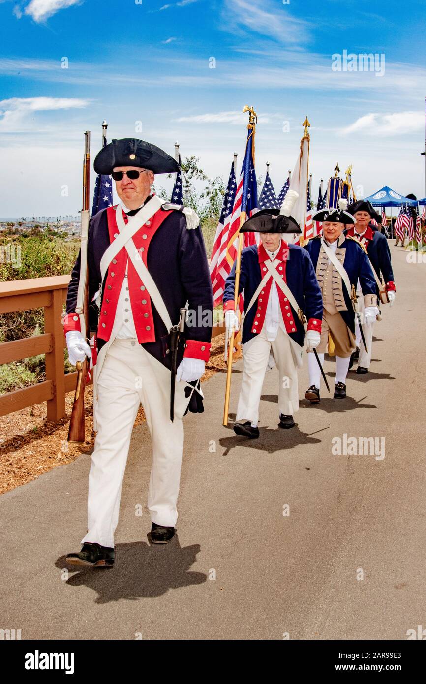 Portant des drapeaux américains et des mousquets historiques, un garde-couleur des uniformes révolutionnaires américains défilés lors d'une célébration du 4 juillet à Newport Beach, Californie. Banque D'Images