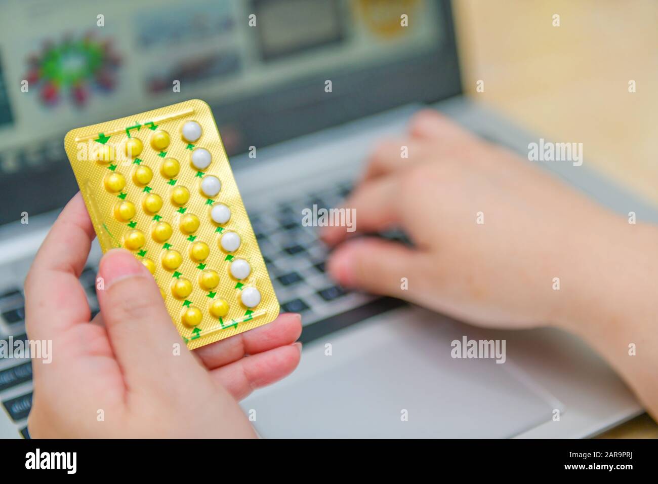 Pharmacien utilisant l'ordinateur portable dans la pharmacie ou la pharmacie. Tenir la main de la boîte de pilules de contrôle de naissance et clé l'ordre de prescription. Banque D'Images