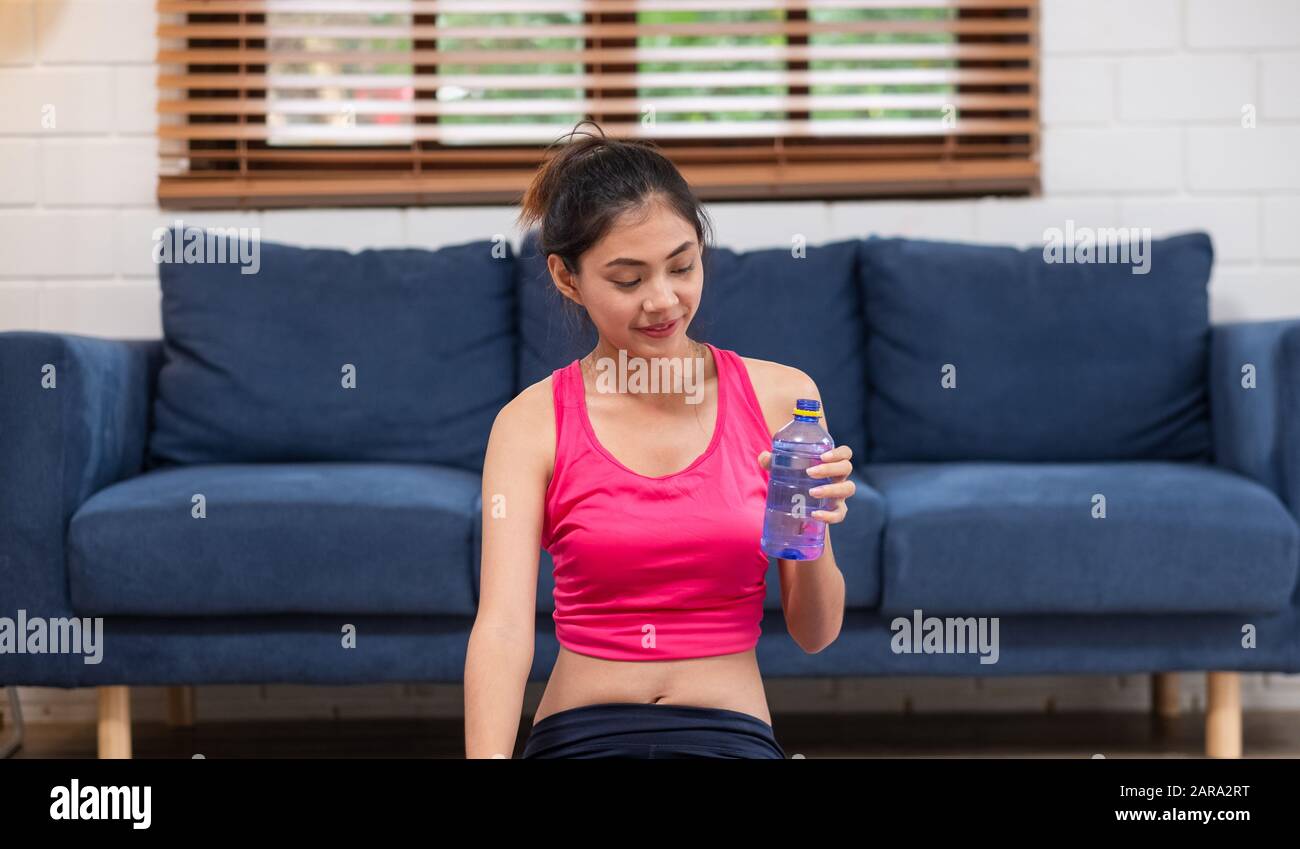 La jeune femme asiatique prend un repos après l'entraînement et boire de l'eau après l'entraînement dans le salon Banque D'Images