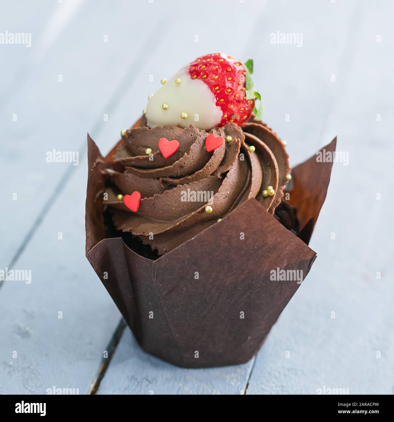 Gâteau au muffin au chocolat avec crème et décoration sous forme de coeur sur fond gris. Concept d'amour de Saint-Valentin. Cadre carré gros plan sélectionné Banque D'Images