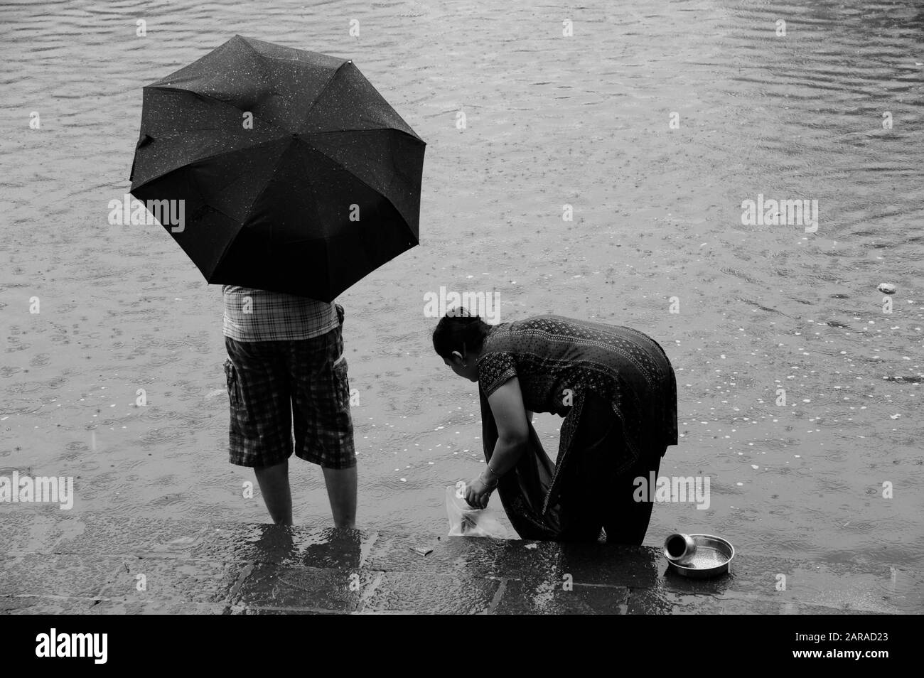 Homme sous parapluie, femme se mouiller, réservoir d'eau Banganga, Walkeshwar, Malabar Hill, Mumbai, Maharashtra, Inde, Asie Banque D'Images