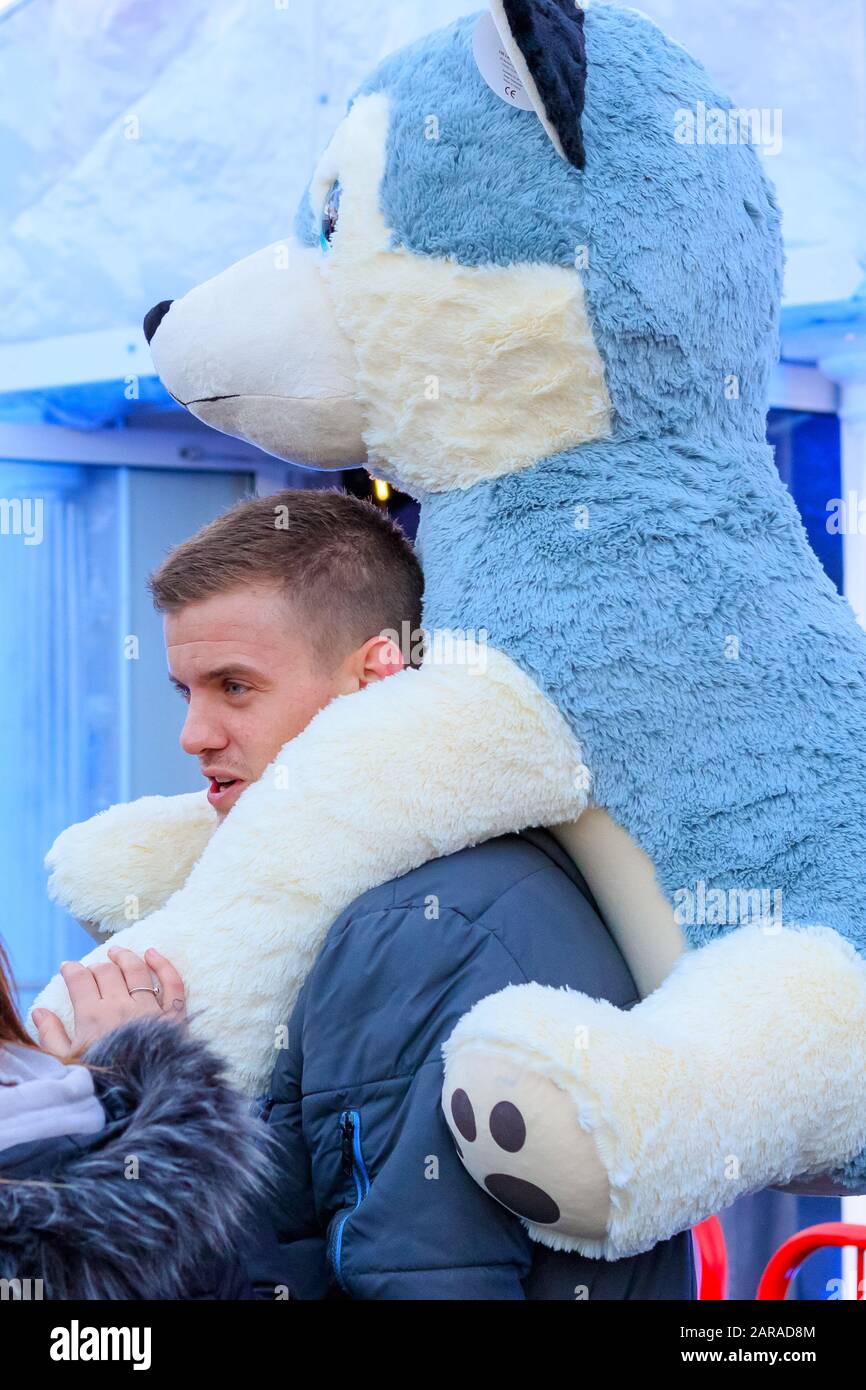 Londres, Royaume-Uni - 27 novembre, 19- une balade touristique masculine avec le grand chien en peluche primé sur son épaule au funkair Winter Wonderland de Noël Banque D'Images