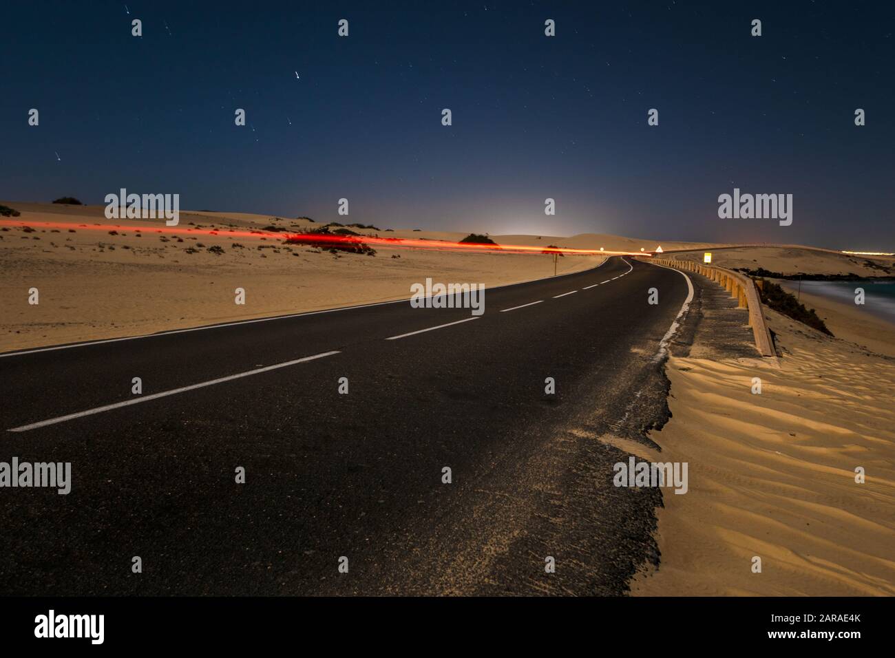 route asphaltée qui traverse le désert sablonneux la nuit Banque D'Images