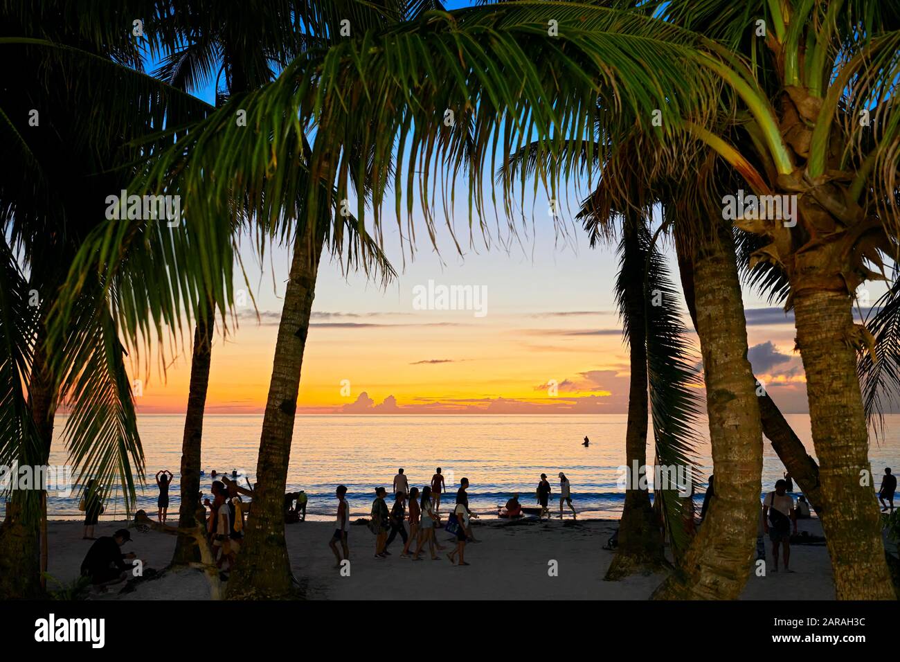 Île de Boracay, province d'Aklan, Philippines : les gens de la plage blanche profitent du coucher du soleil. Palmiers encadrant l'image. Banque D'Images