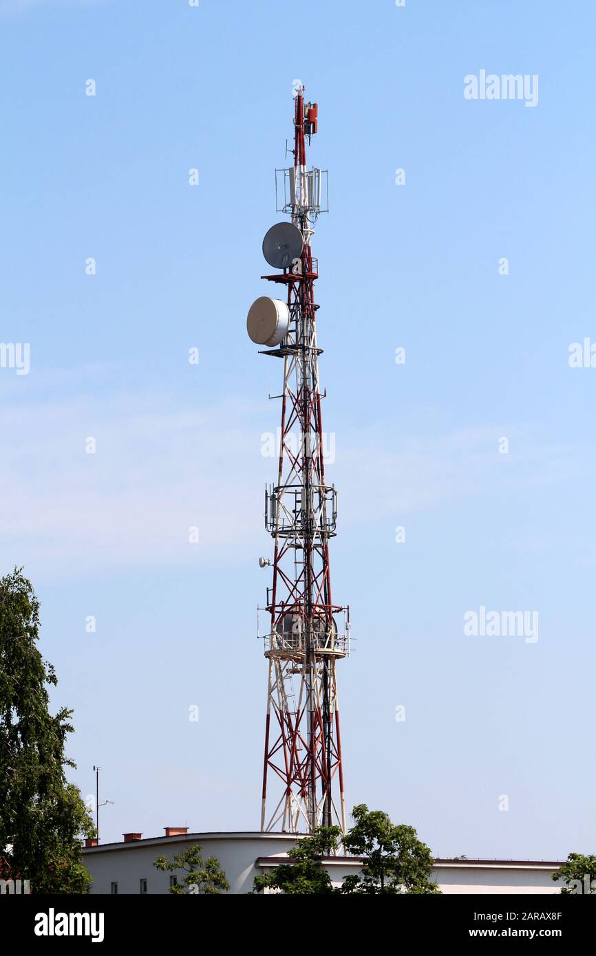 Grande tour d'antenne rouge et blanche avec plusieurs antennes et émetteurs  sur le dessus du bâtiment de bureau, qui monte au-dessus des arbres Photo  Stock - Alamy