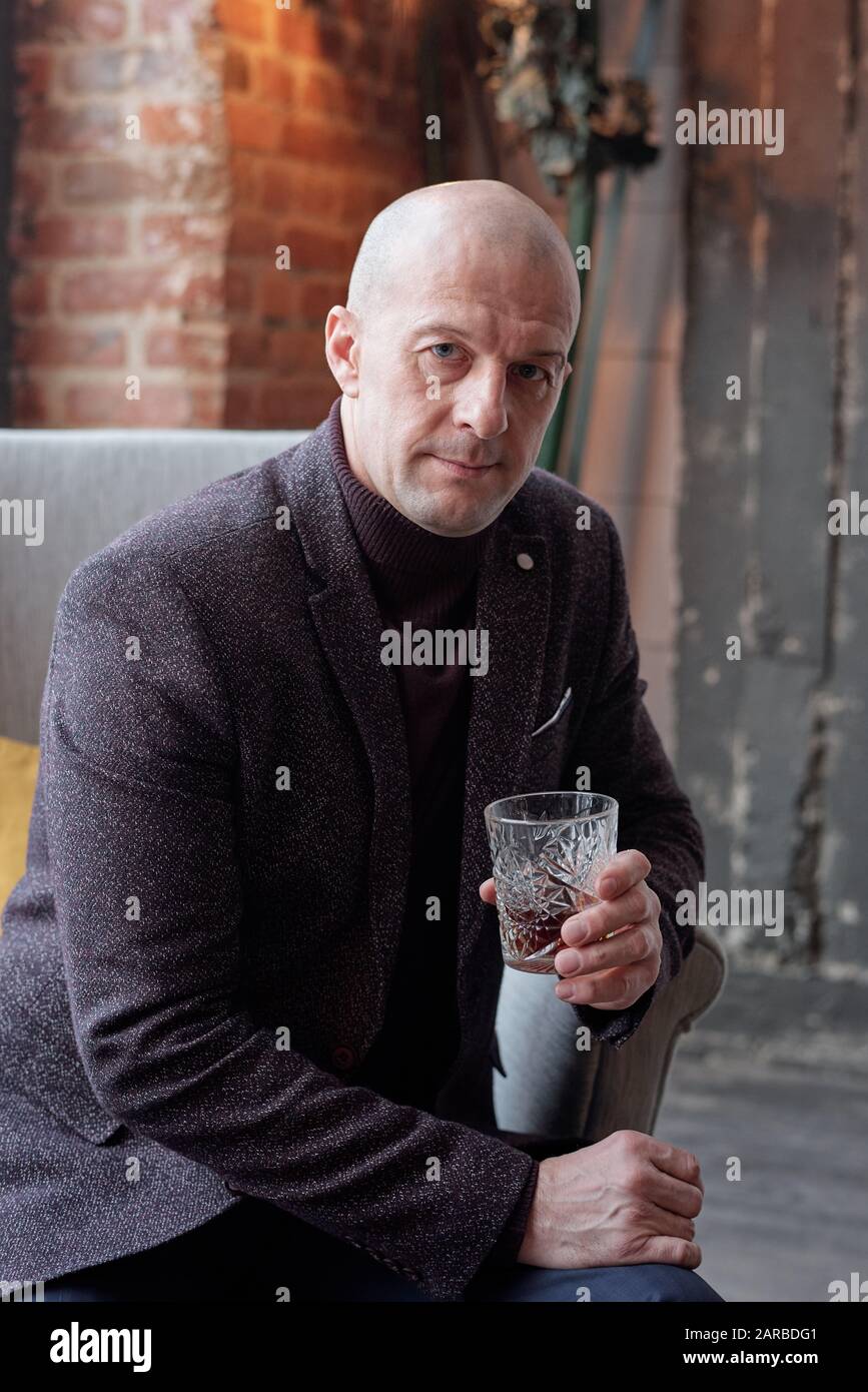 Bald homme d'affaires avec un verre de liqueur dure Banque D'Images