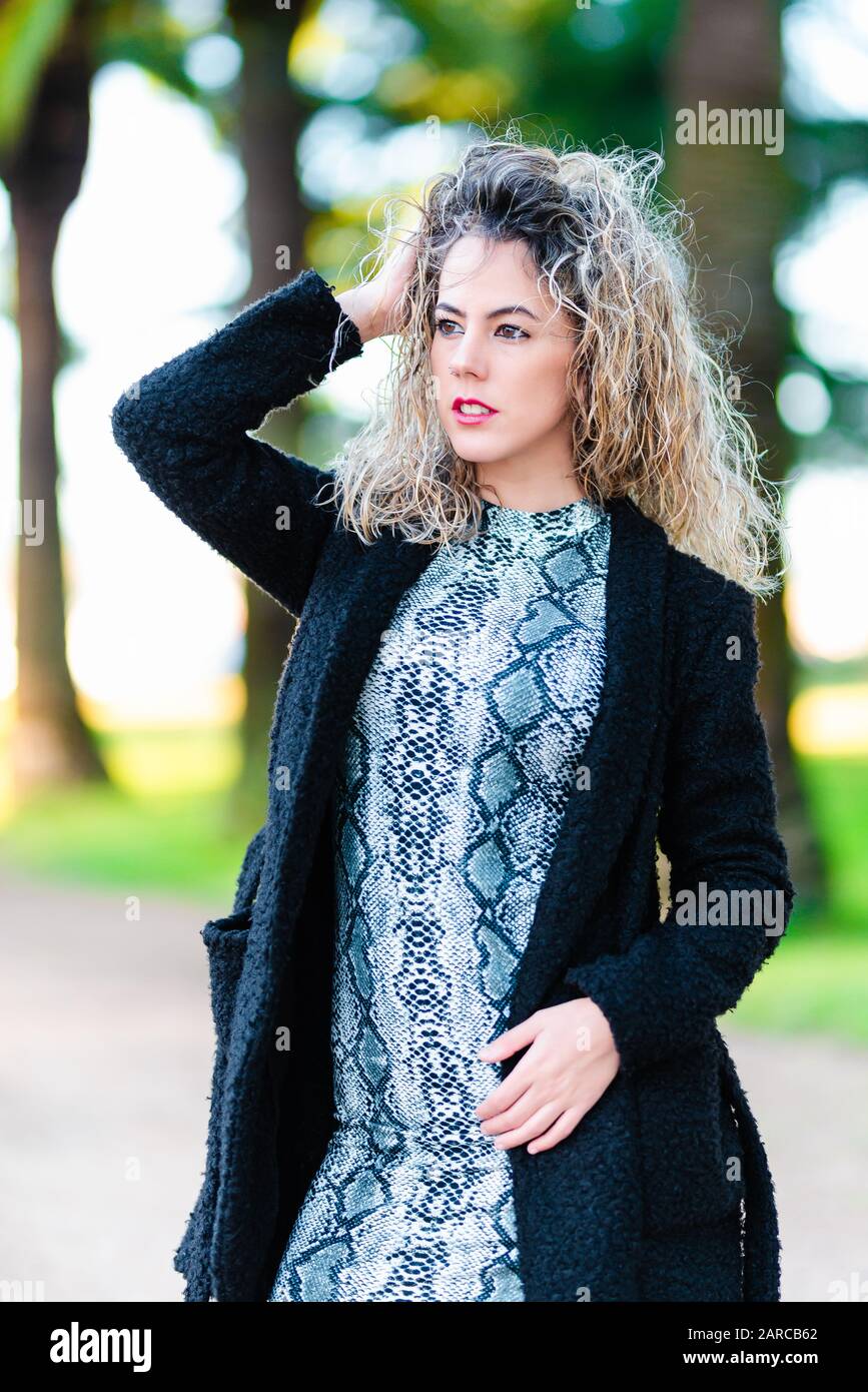 Modèle de jeune femme avec des cheveux blonds frisés posant dans le parc Banque D'Images