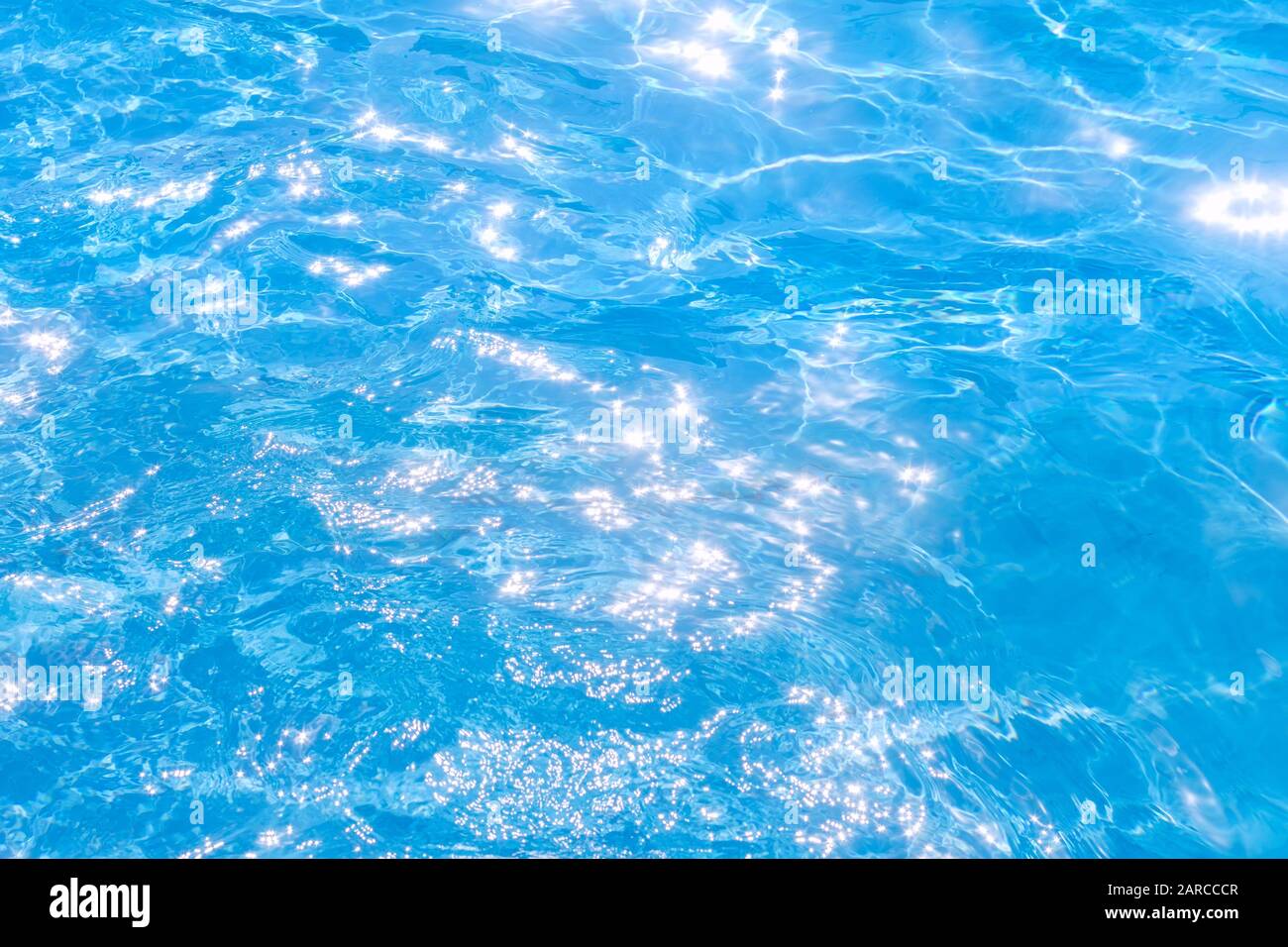 Eau déchirée bleue dans la piscine. Arrière-plan la surface de l'eau. Texture, eau bleue, rayons lumineux du soleil Banque D'Images