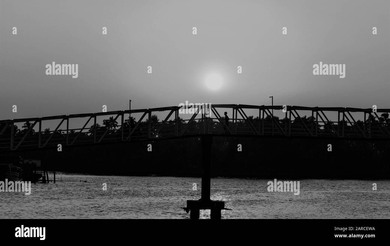 Silhouette d'un pont au crépuscule avec beau coucher de soleil et fond de ciel rouge étendu, noir et blanc Banque D'Images
