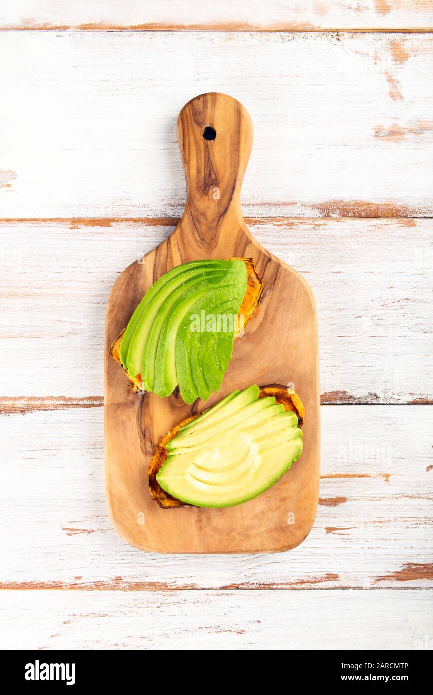 Toasts de pommes de terre douces avec avocat, œufs durs, tomates et graines de sésame sur carton en bois. Concept de repas sain. Cuisine propre, cuisine végétarienne, vue sur le dessus Banque D'Images