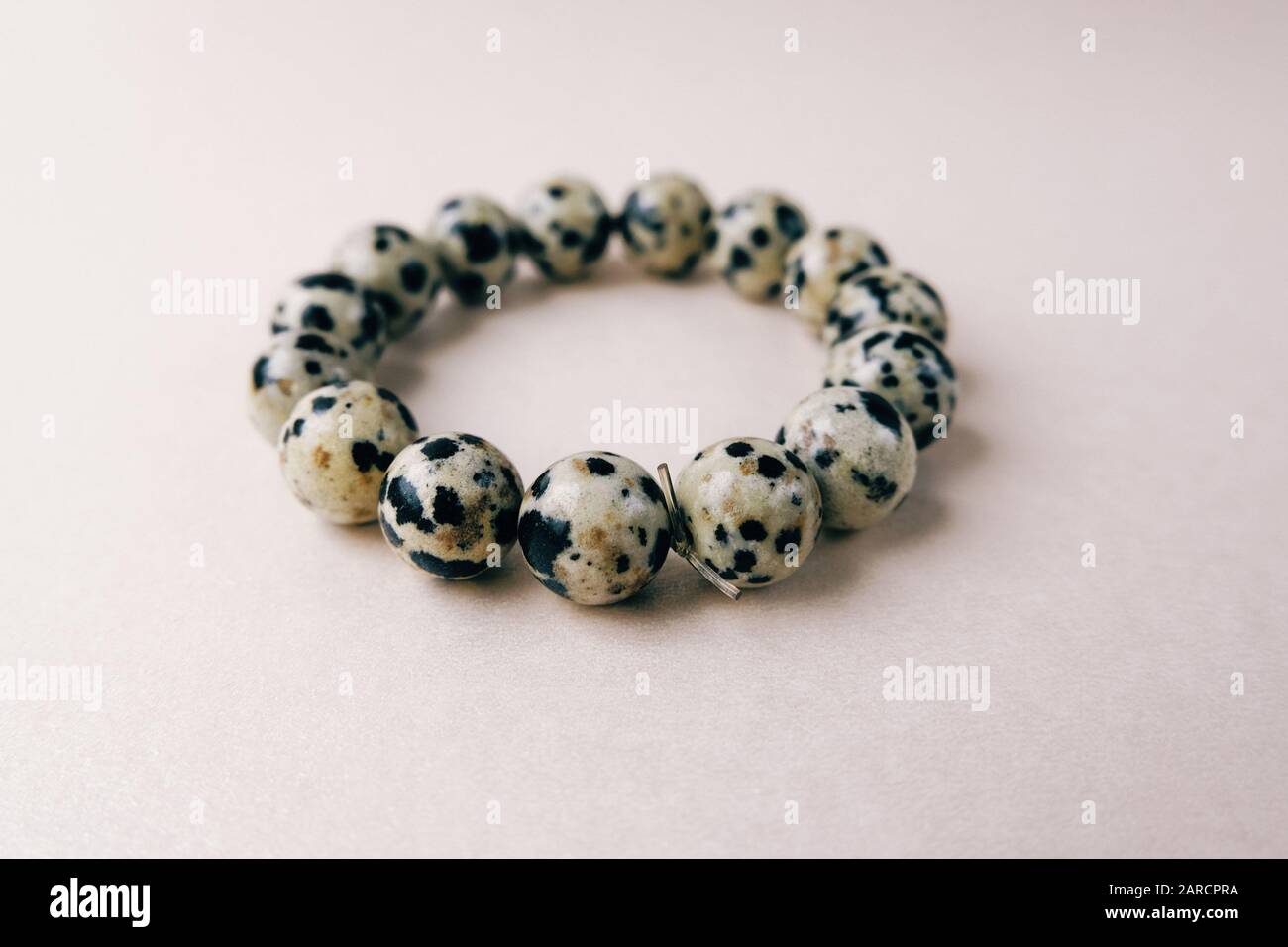 Pierres de pierres artisanales dalmatienne jasper bracelet décoration produit crème mensonges fond doré. Accessoire de mode perles ornement les mains. Banque D'Images