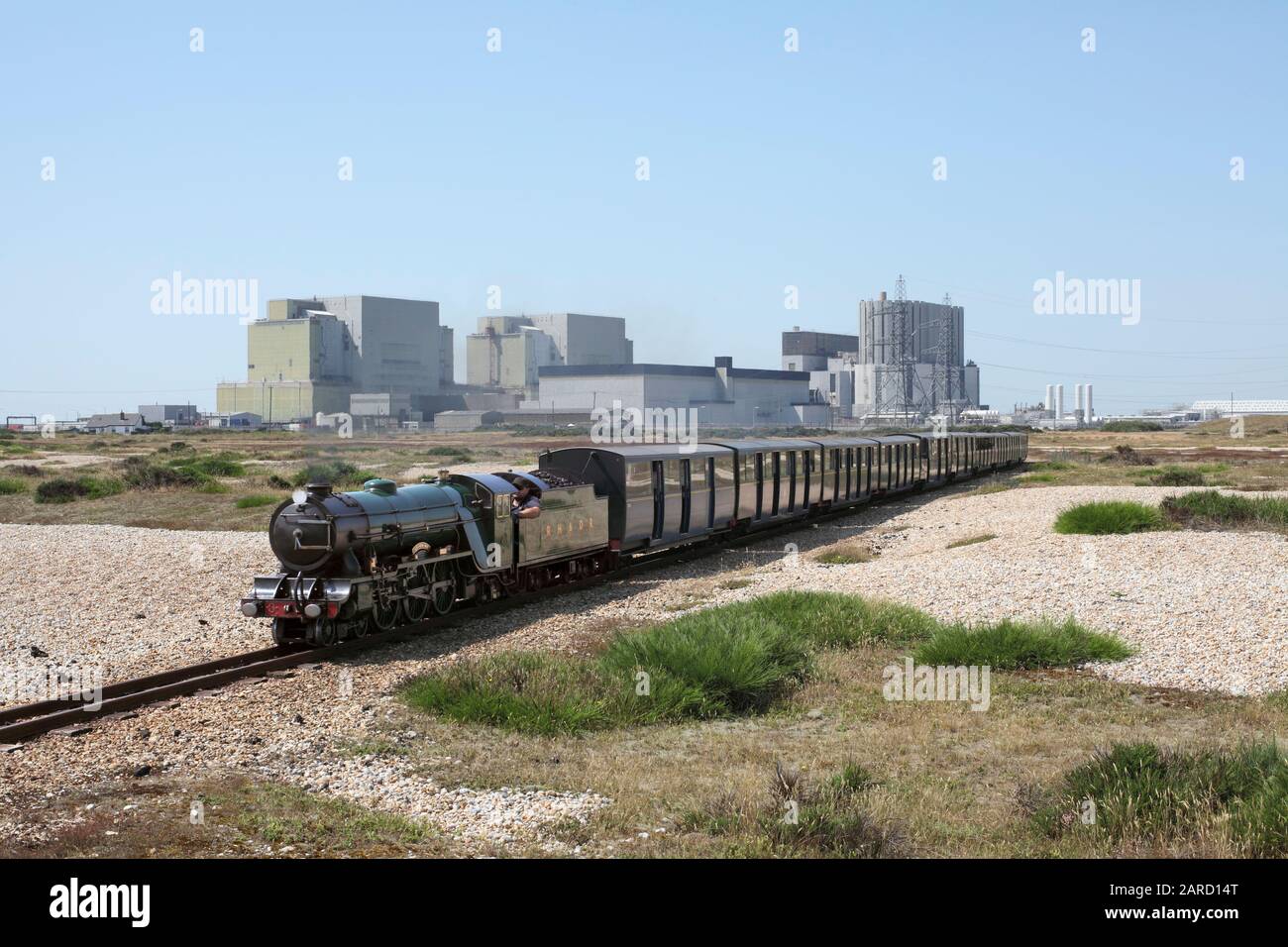 Un train à vapeur sur les chemins de fer Romney, Hythe et Dymchurch se dirige vers l'est de Dungeness, avec les centrales nucléaires Dungeness A & B en arrière-plan. Banque D'Images