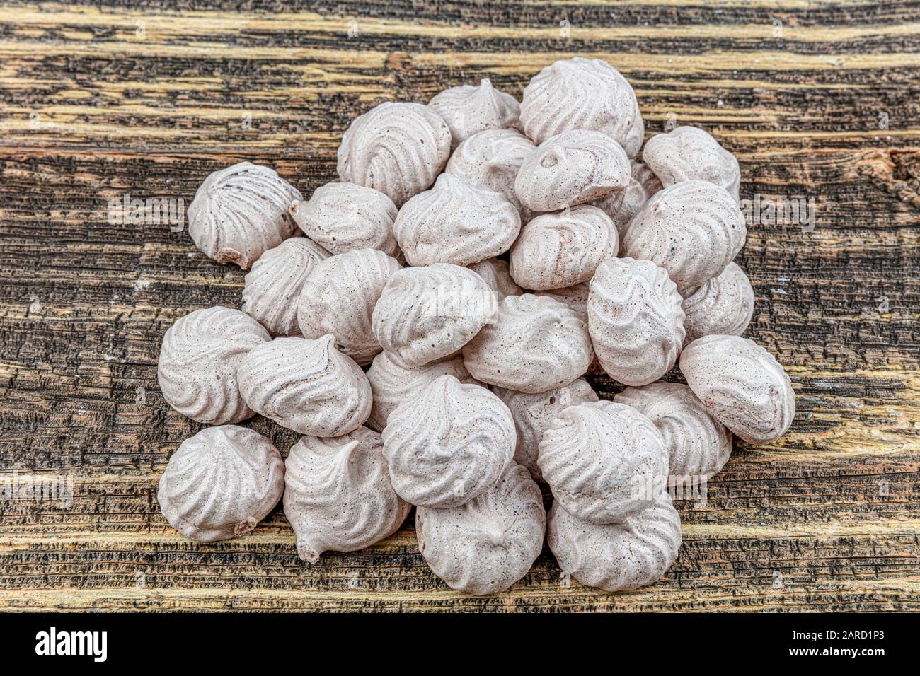Gâteau meringue à tourbillon blanc, fouetté, gris et rose nommé Pavlova dans le processus de préparation. Tourbillons de beze blancs, gris et roses sur table en bois. Banque D'Images