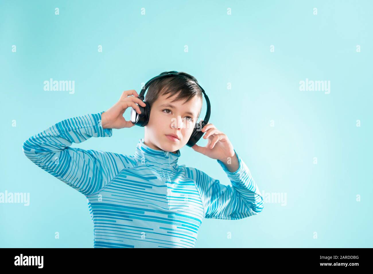 Enfant appréciant de la musique sur son casque, en écoutant de la musique. Beau jeune enfant élégant dans un casque debout sur fond bleu Banque D'Images