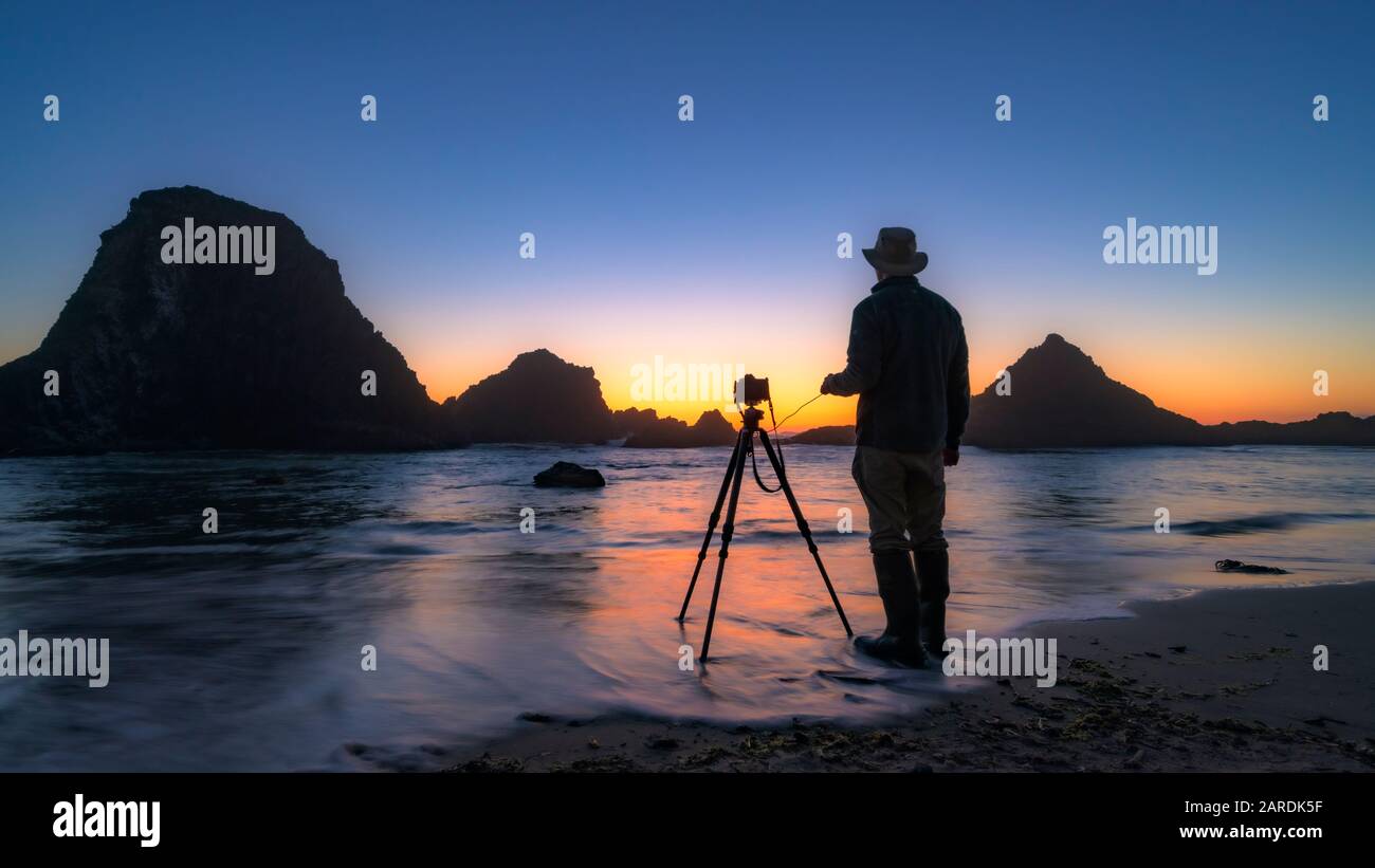 Alex Morley photographiant des piles de mer au coucher du soleil au parc national Seal Rock, sur la côte centrale de l'Oregon. Banque D'Images