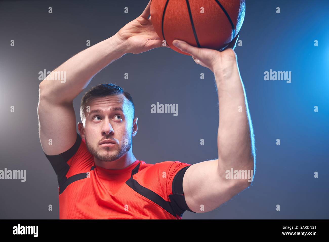 Jeune homme athlétique préparé pour lancer le ballon de basket-ball avec  des lumières sur fond Photo Stock - Alamy