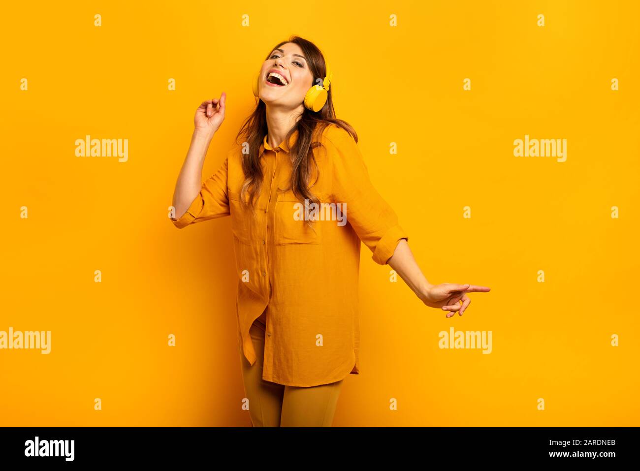 Fille avec casque jaune écoute de la musique et des danses et énergique expression émotionnelle. Banque D'Images
