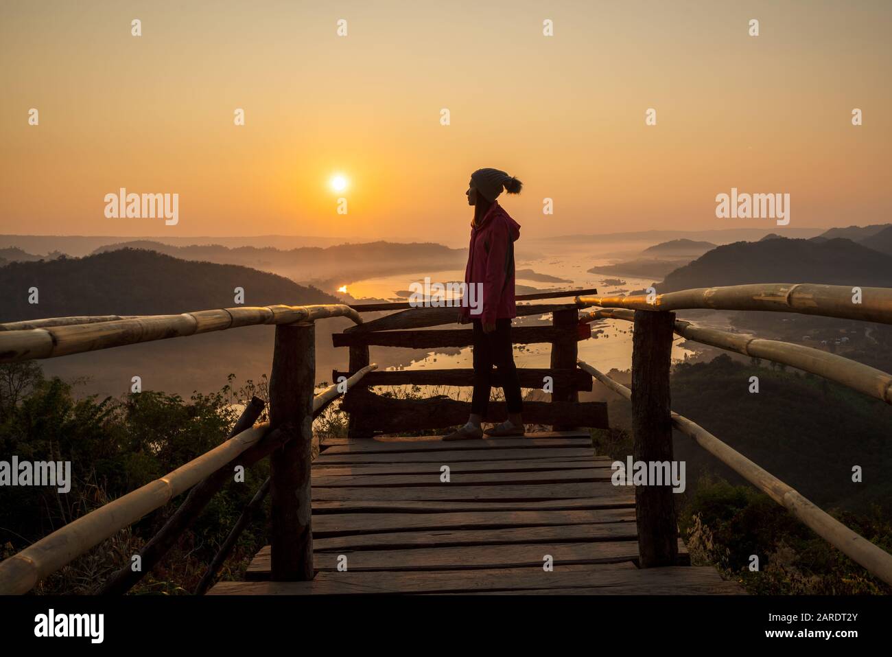 Femme profitant du lever du soleil sur le fleuve Mékong et debout sur le pont en bois seule elle Banque D'Images