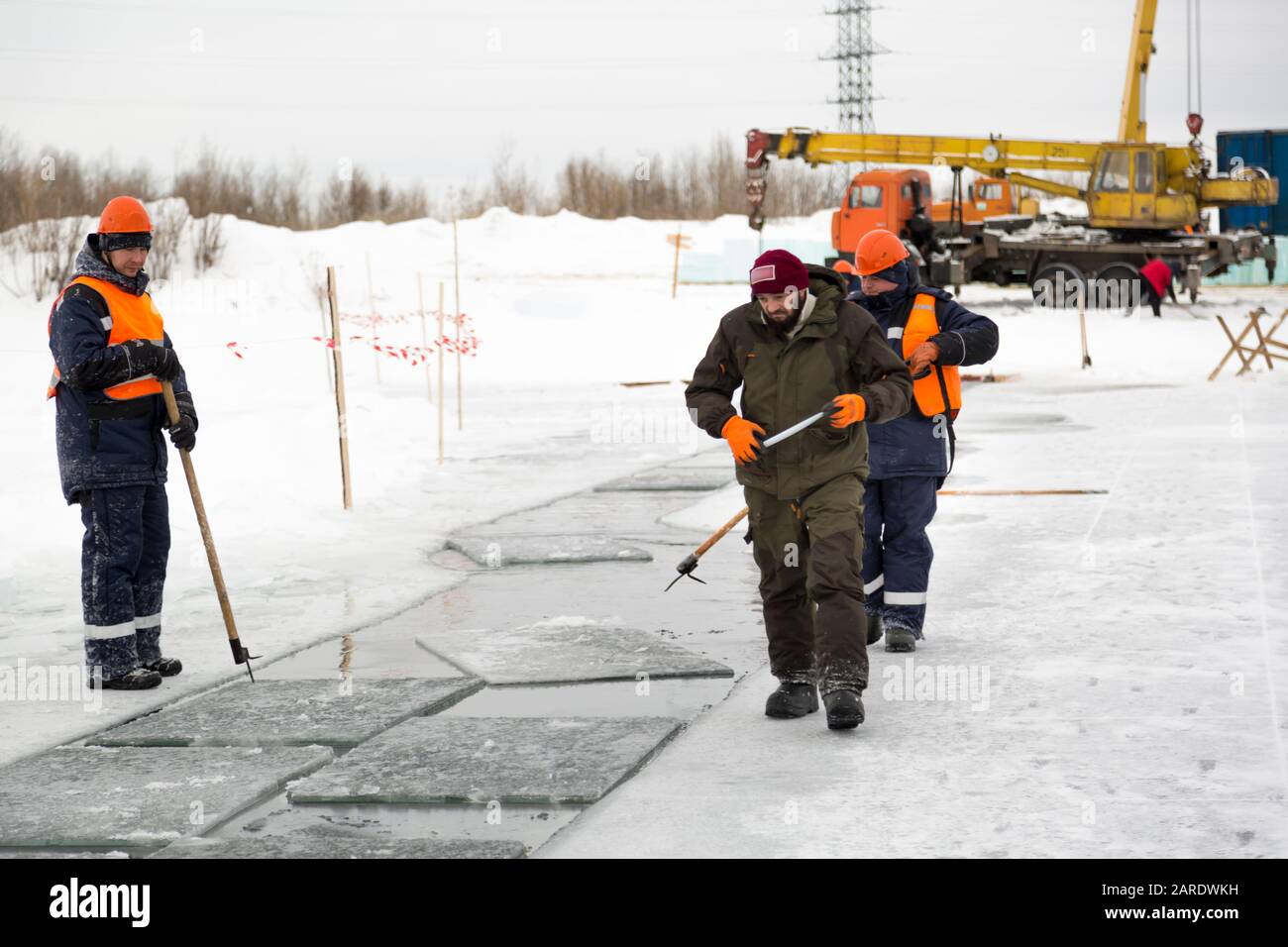 Les employés radeau des blocs de glace le long d'une chaîne coupée un lac gelé Banque D'Images