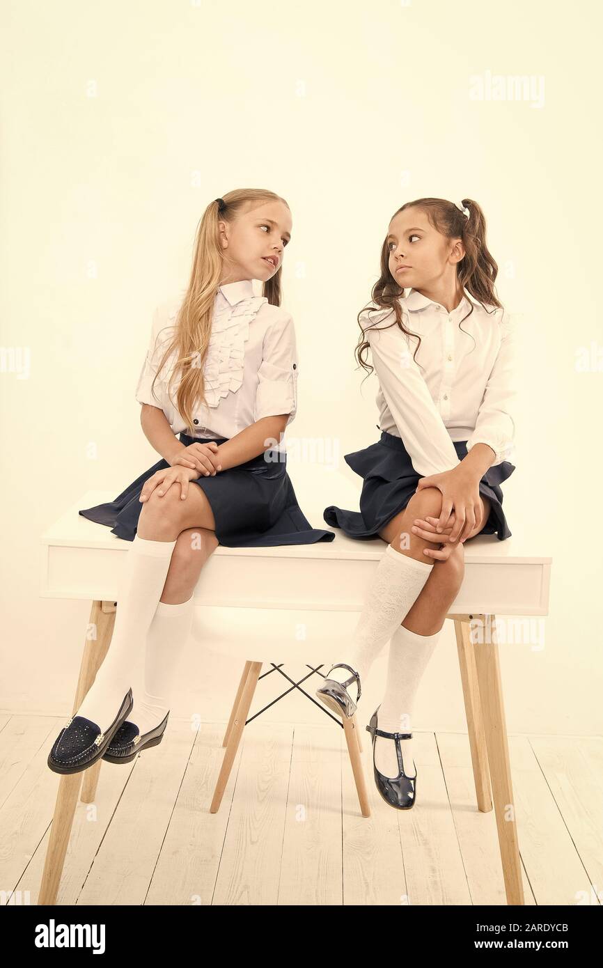 Se préparer pour la rentrée scolaire. Les élèves de l'élémentaire en uniforme officiel assis sur table. Peu d'écolières parler en classe de l'école. Les petits enfants de l'école bénéficiant d'une pause. Banque D'Images