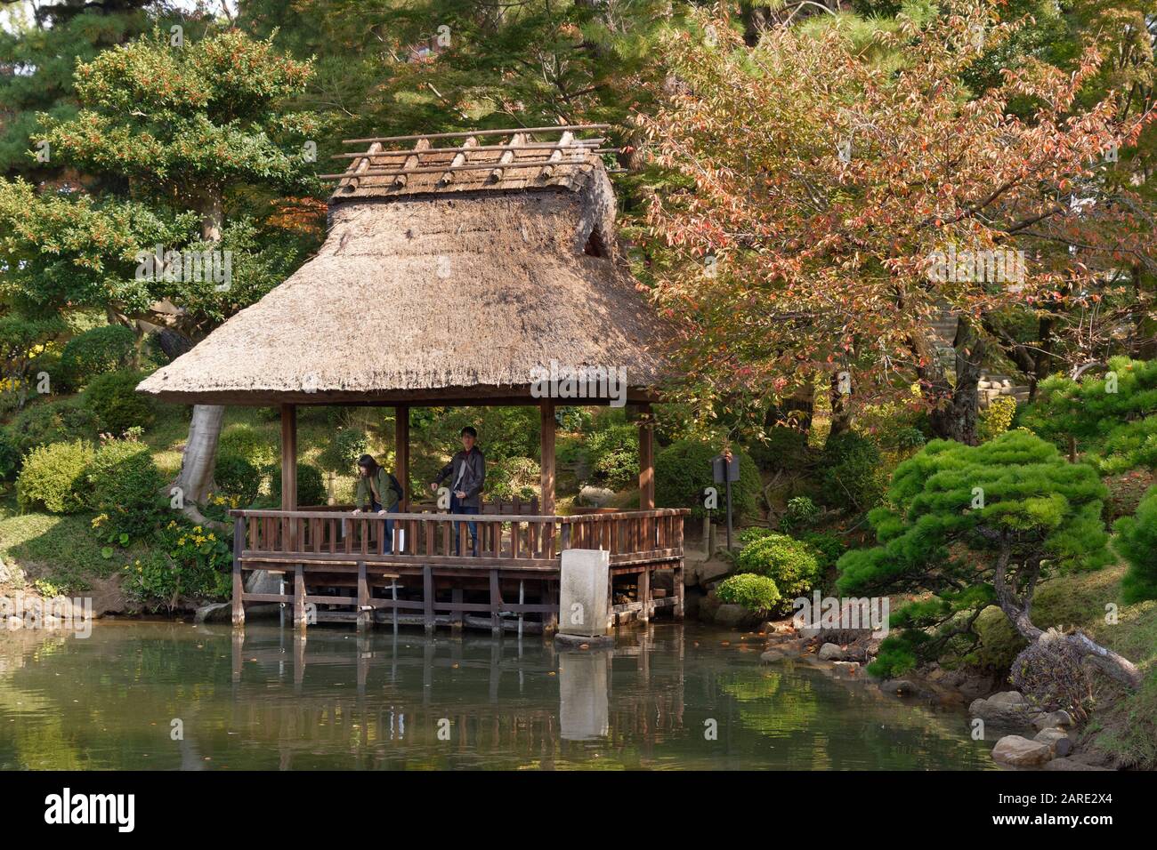 Pavillon côté étang à chaume à Shukkei-en Garden (jardin de paysages "hrunken"), Hiroshima, Japon, un jardin japonais traditionnel Banque D'Images