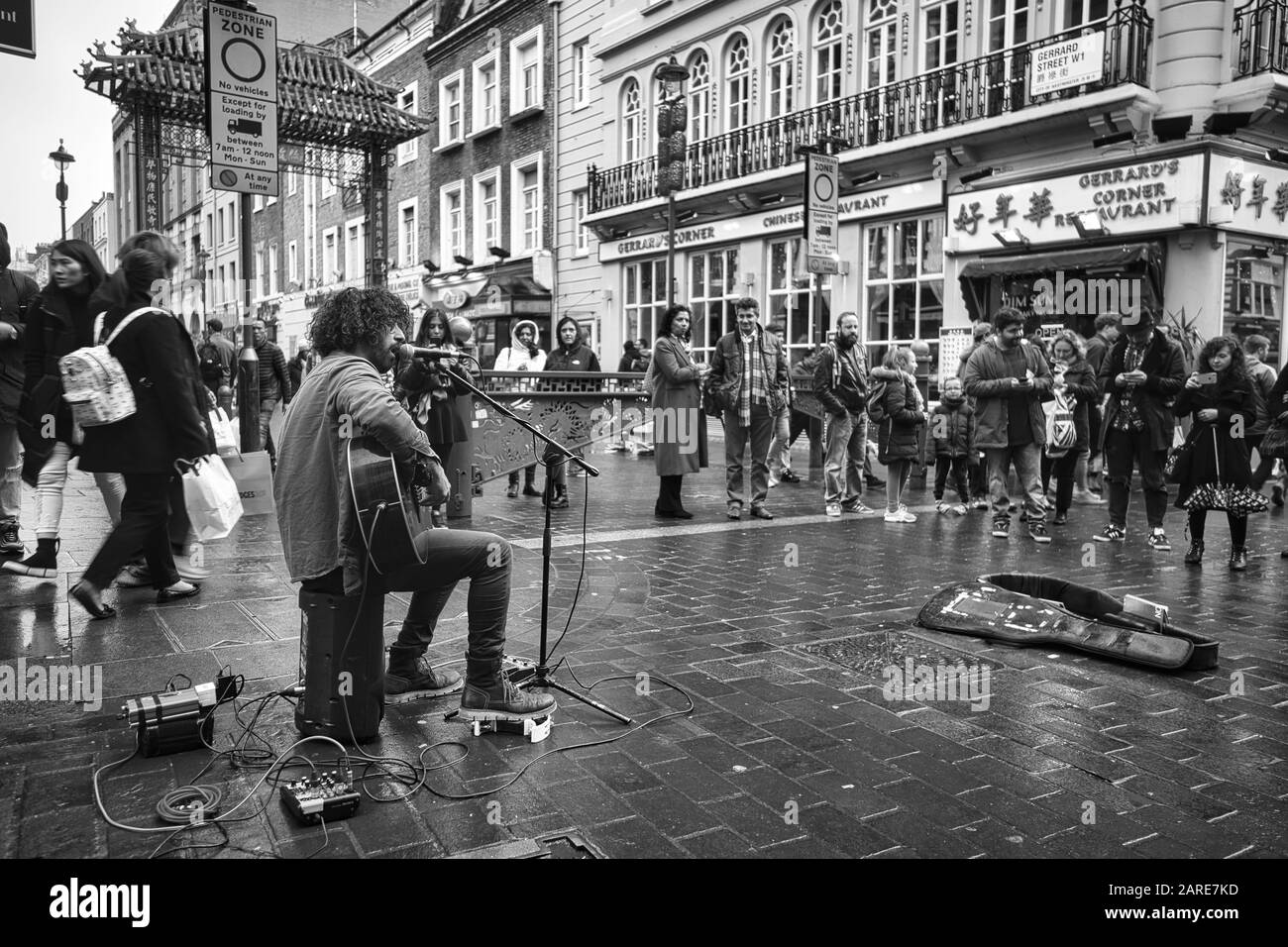 Londres, ROYAUME-UNI - 11 avril 2019 : un cliché en niveaux de gris de personnes se sont rassemblées autour d'un musicien chantant dans les rues de Londres Banque D'Images