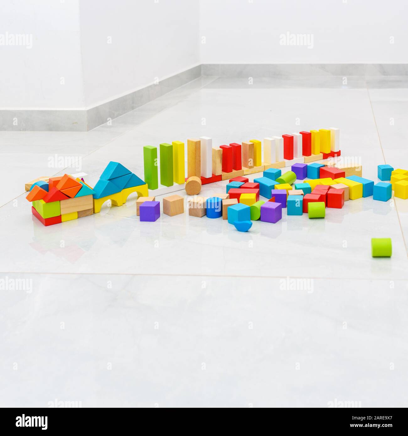 Différentes couleurs et formes de jouets en bois blocs de construction dans la maison sur le sol de tuiles grises. Banque D'Images
