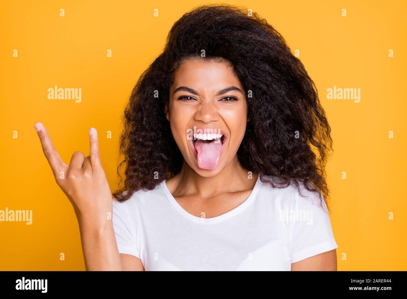 Photo D Une Jeune Fille Folle Ebourieuse Et Emouillee Qui S Est Enortie De La Langue Avec Des Doigts Cornes Signe De Roche Qui Criait Isole Dans Un T Shirt Blanc Aux Couleurs Eclatantes Photo