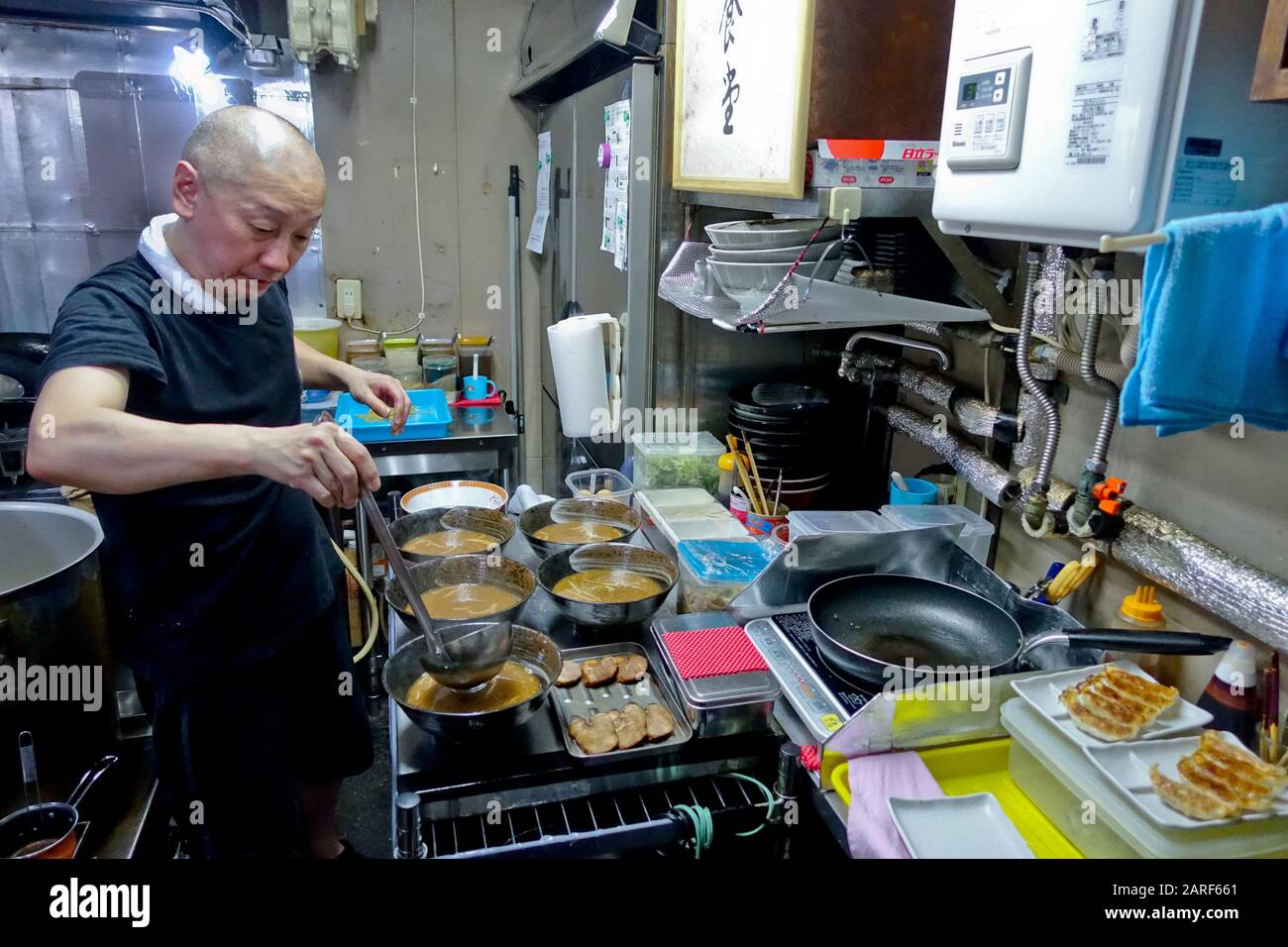 Un chef ramen prépare des ramen, un plat japonais de nouilles servi dans un bouillon à base de viande ou de poisson pour un groupe de quatre. Banque D'Images