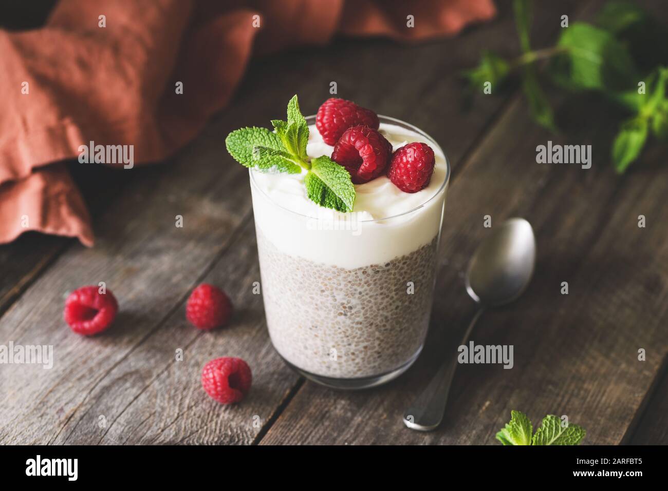 Boudin de Chia dans un pot en verre avec framboises et yaourt grec sur une table en bois. Repas végétarien ou en-cas sains pour le petit déjeuner Banque D'Images