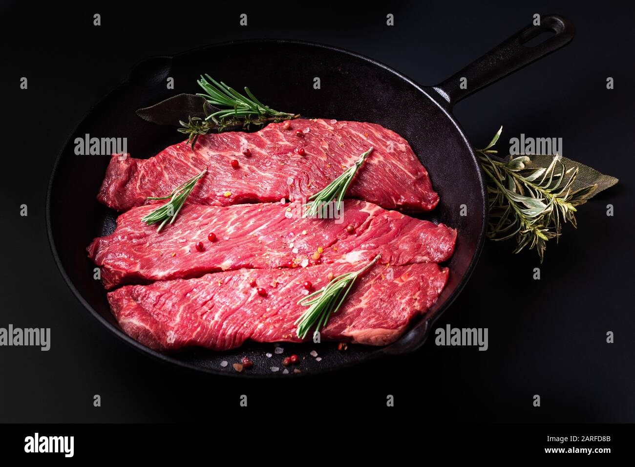 Concept de nourriture viande crue bio filet de boeuf steak dans poêle à frire poêle sur fond noir Banque D'Images