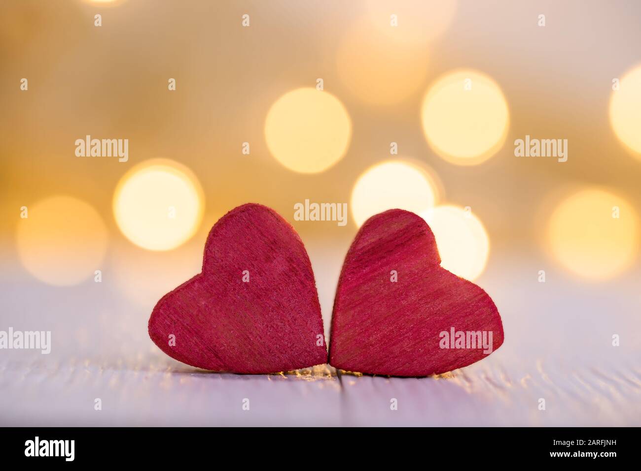 Contexte de la Saint Valentin. Deux coeurs rouges en bois avec des lumières bokeh en arrière-plan et espace de copie. Banque D'Images