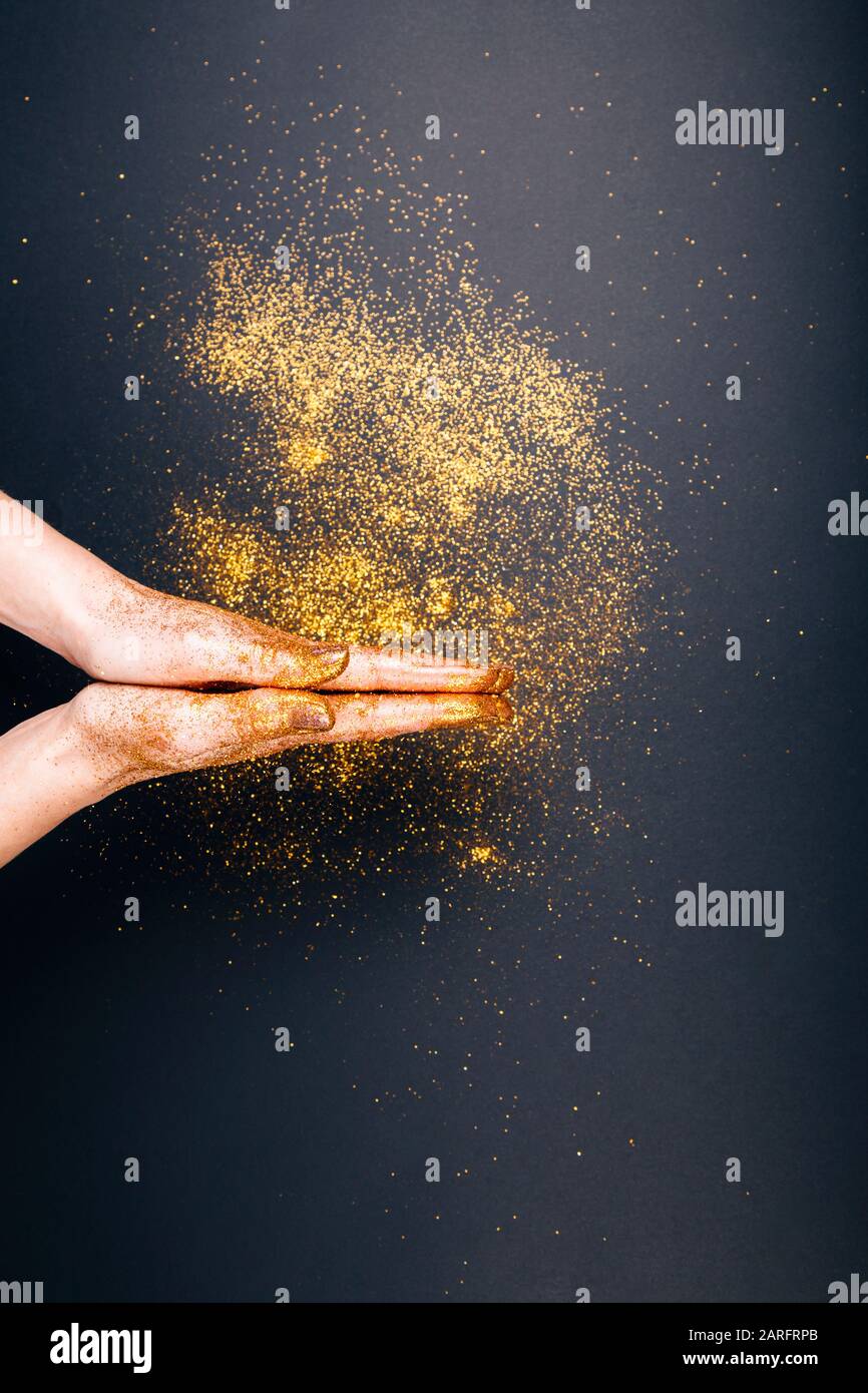 Prier Les Mains dans des paillettes dorées sur fond noir Banque D'Images